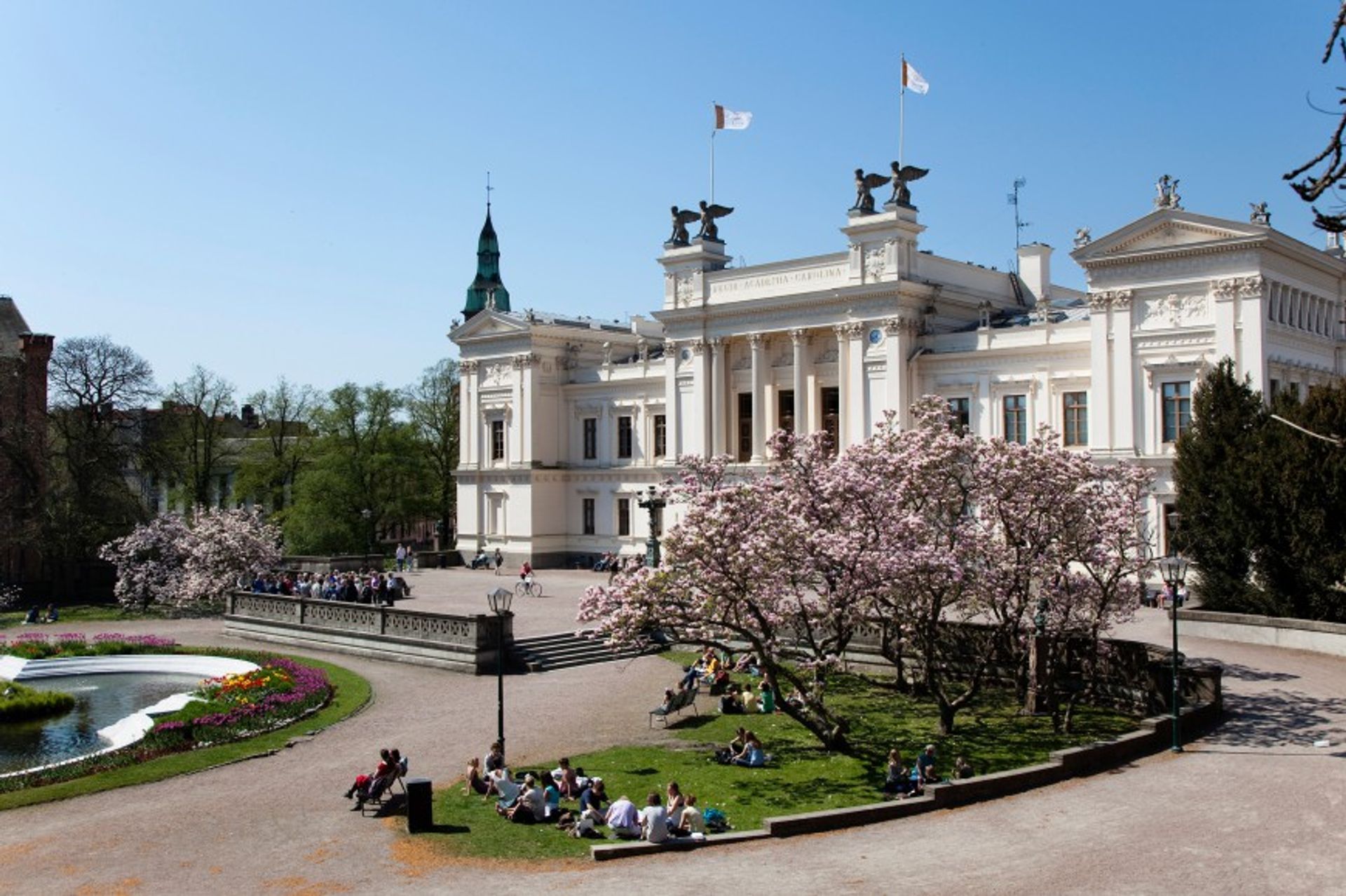 Students sitting on the grass outside of Lund University's main building.