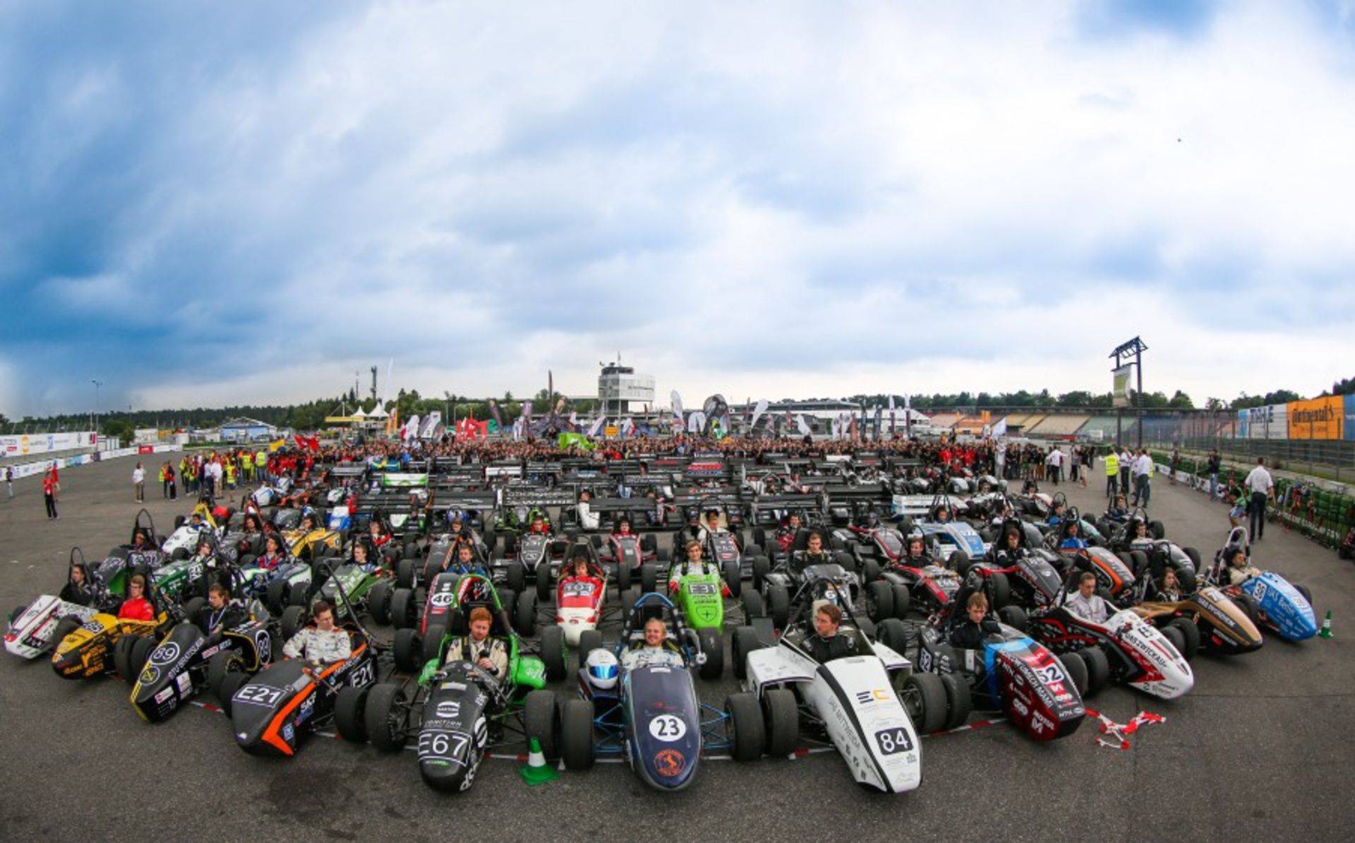 An image of the Formula Student in Germany outside with many Formula One cars.