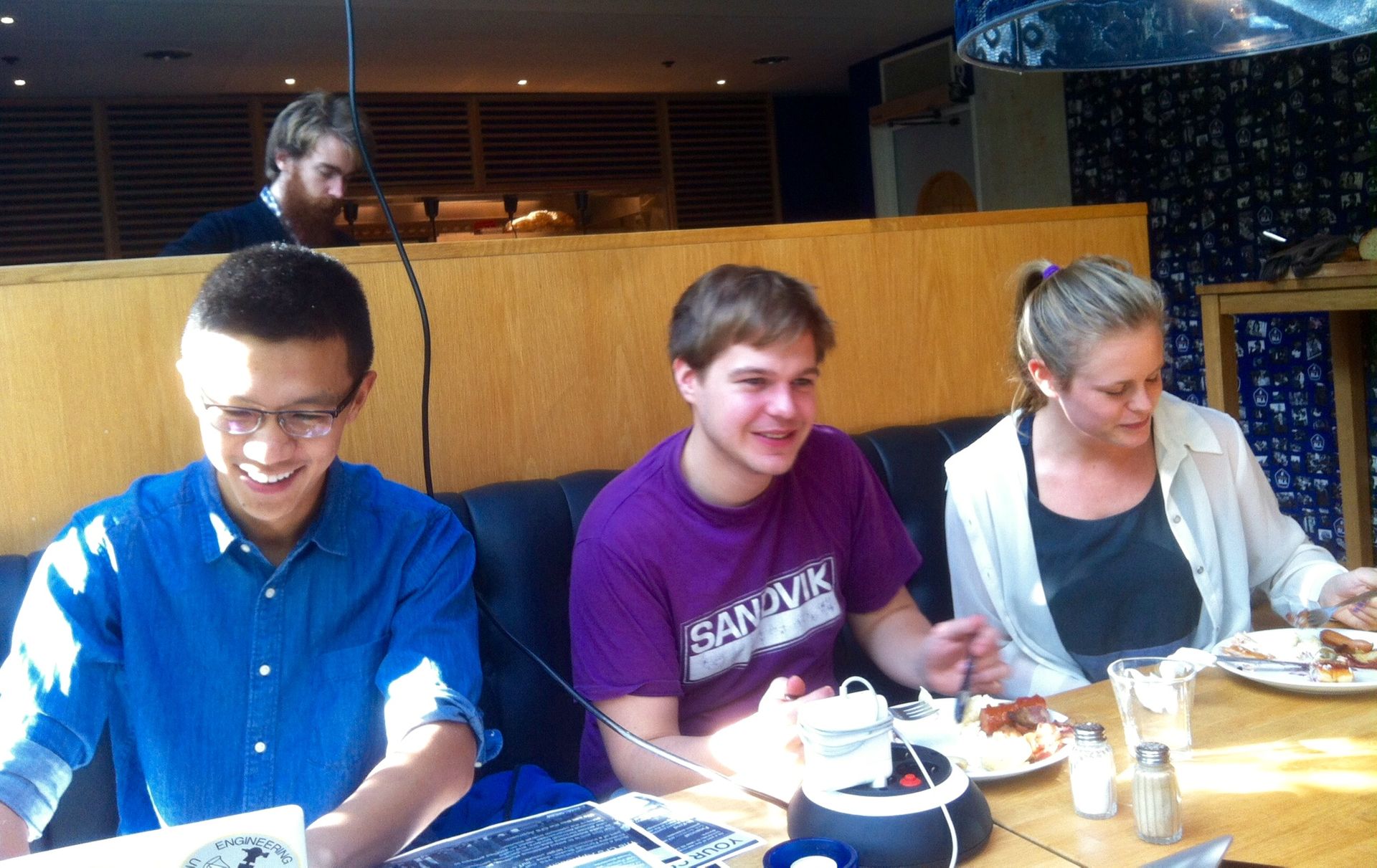 Three male students sitting at Chalmers University of Technology eating buffet food