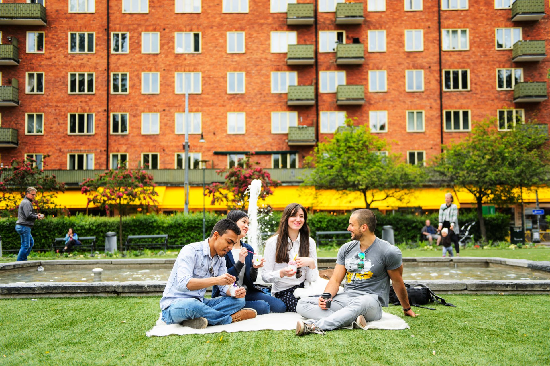 Friends relaxing in a park called Nytorget, eating ice cream, and drinking coffee in Stockholm.