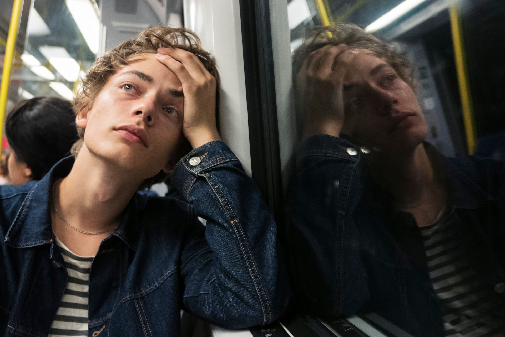 Teenager sitting on a subway thinking about the decisions about their education and future career.