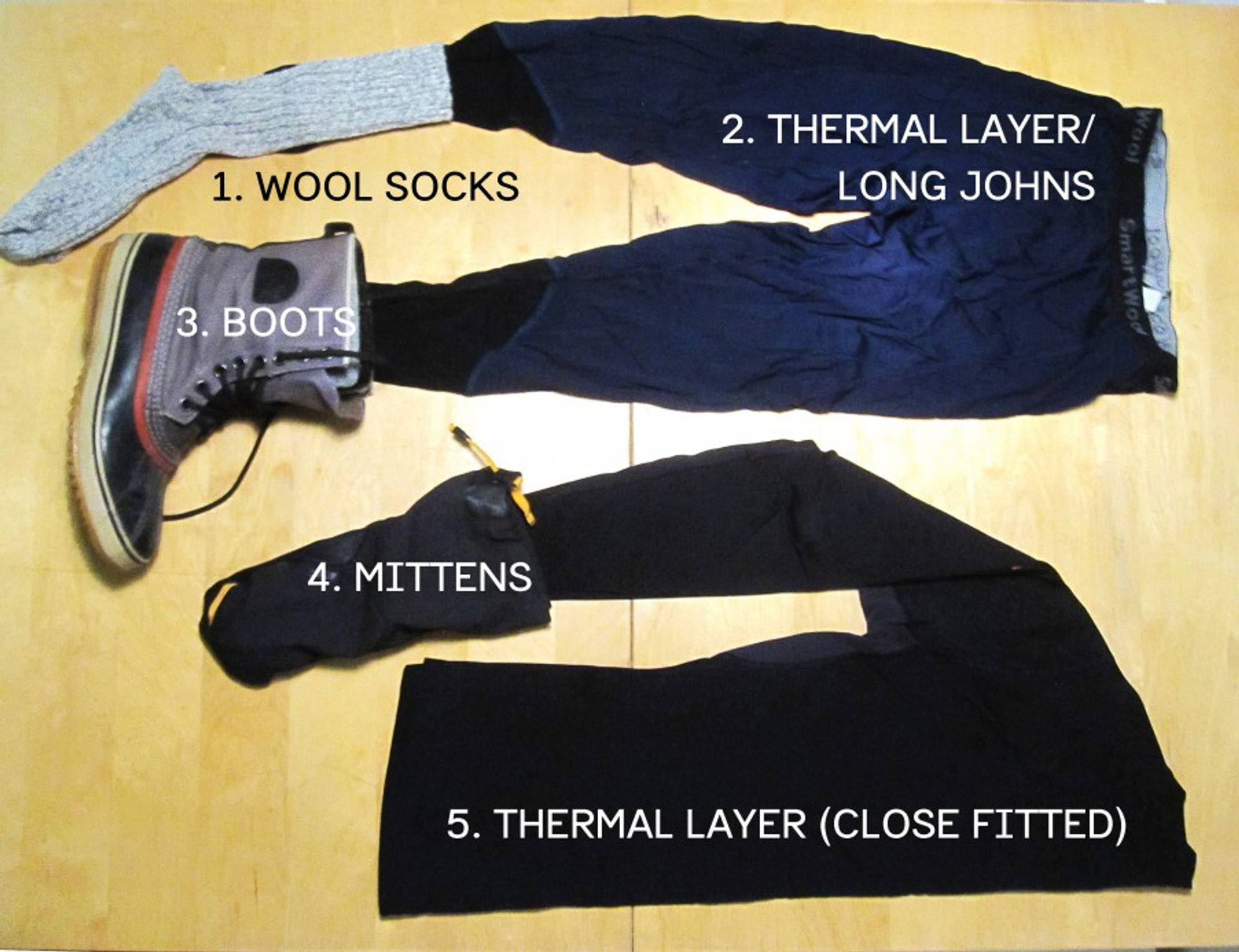 Assortment of clothing including wool socks, mittens and thermal layers.