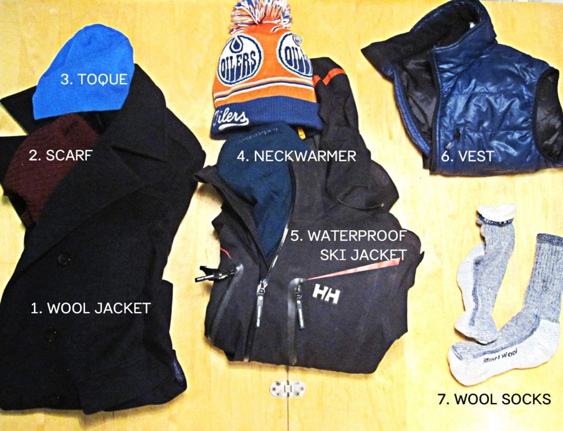 Assortment of clothes including vest, scarf, wool jacket, wool socks and waterproof ski jacket.
