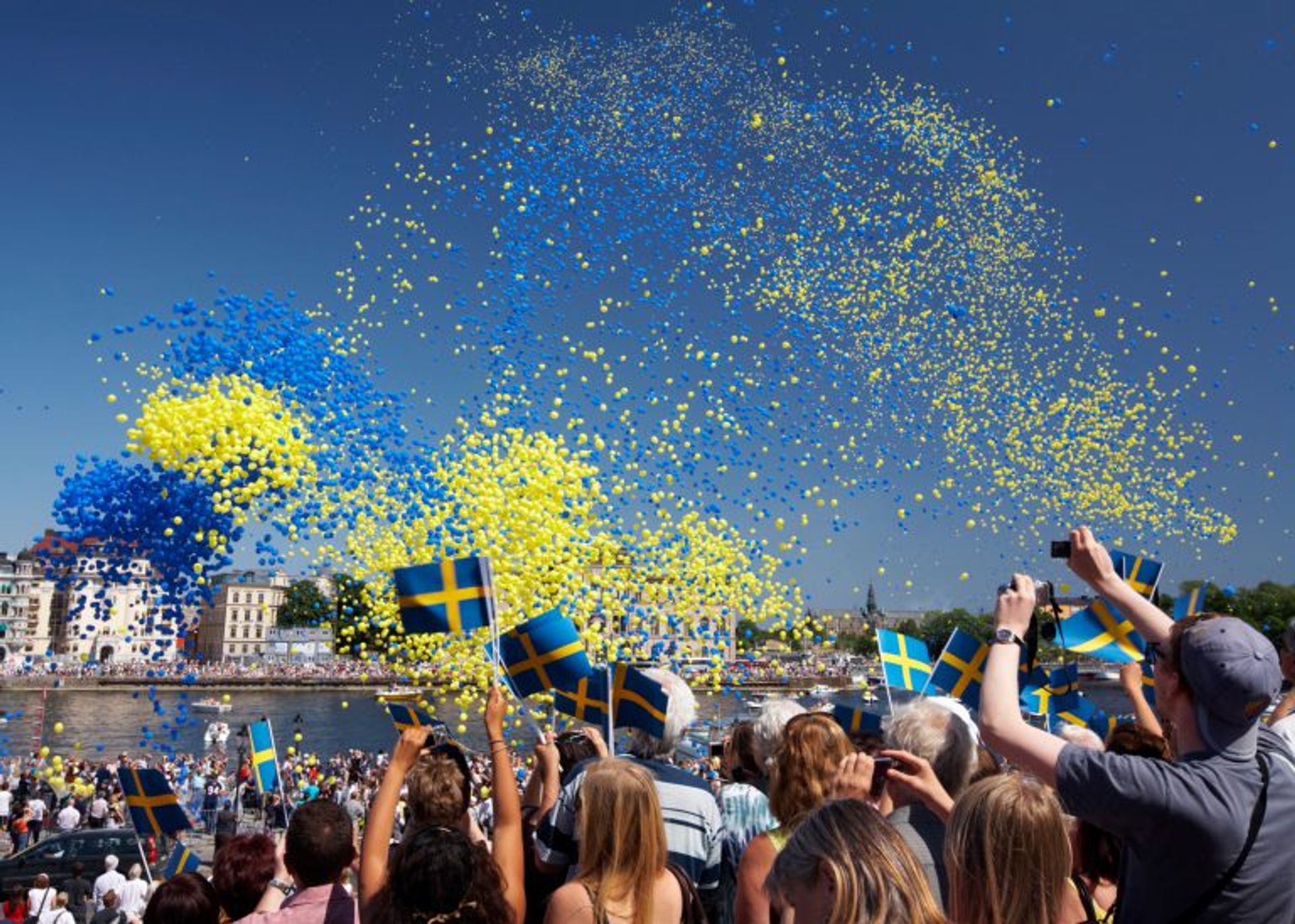 People waving Swedish flags in celebration.