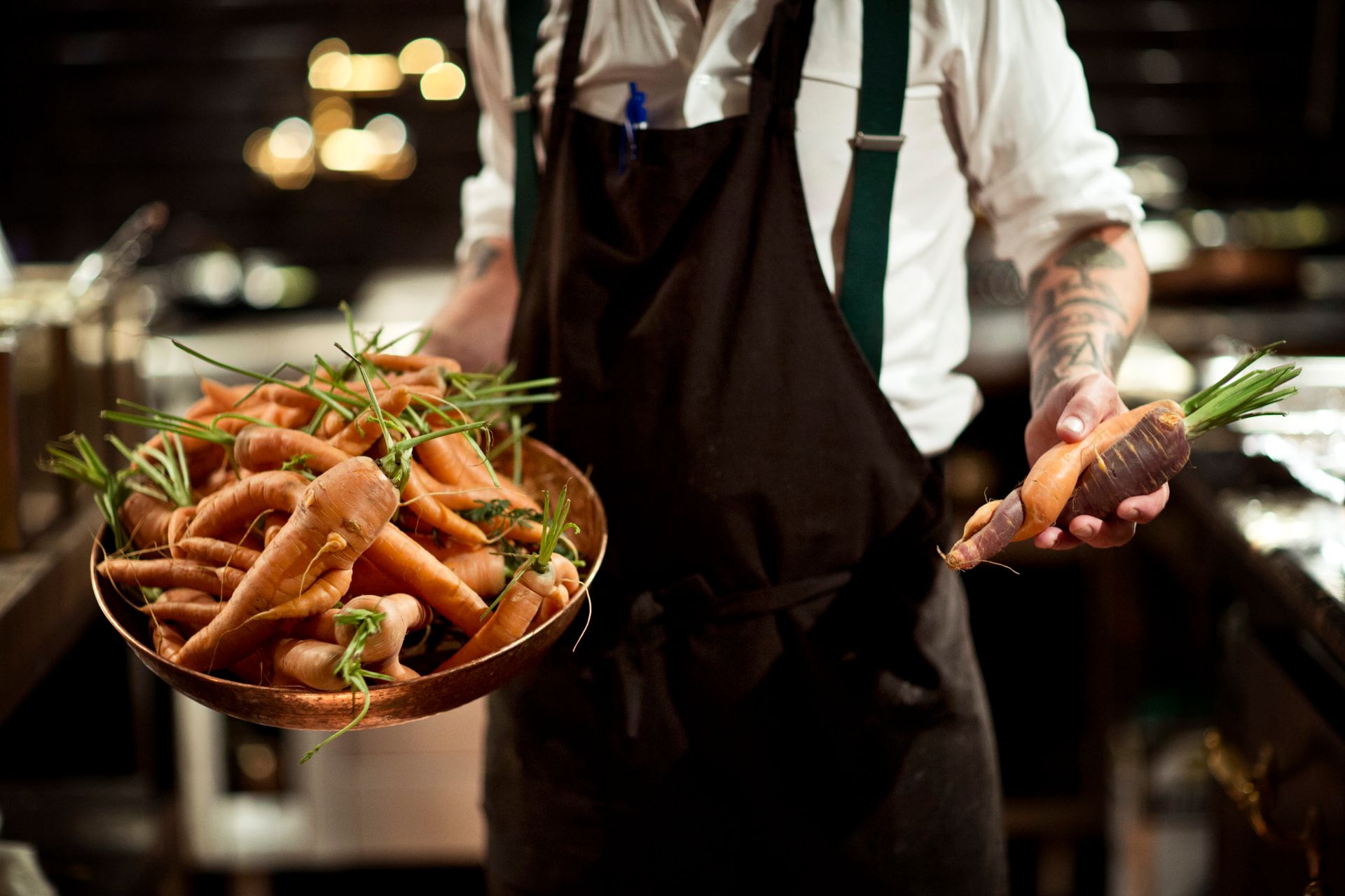 Chef at a restaurant holding a tray full of carrots.