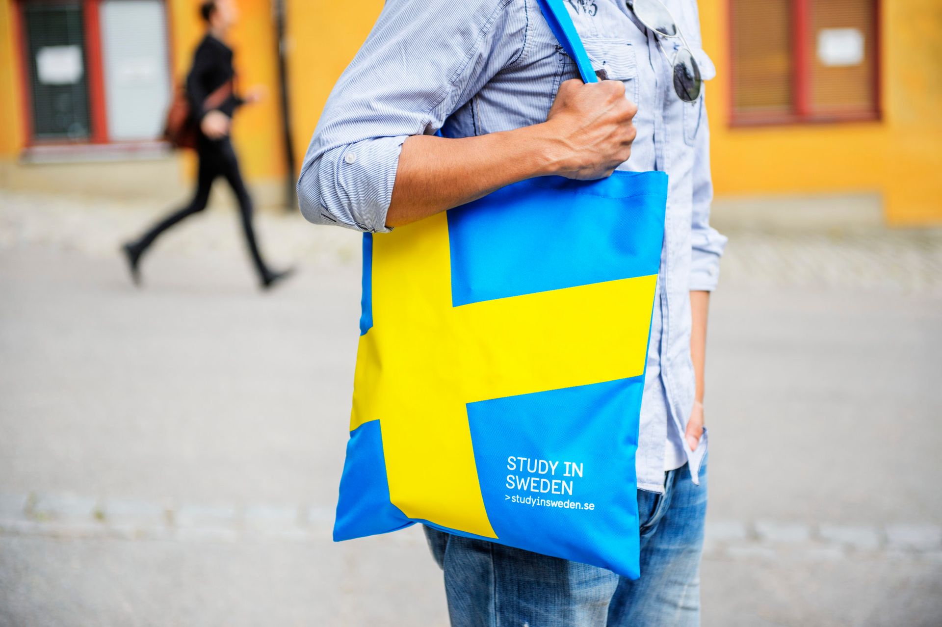 Person holding a blue and yellow tote bag.