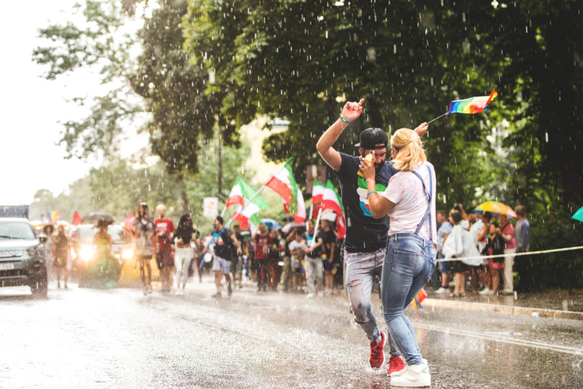 Two people in a street waving flags and dancing.