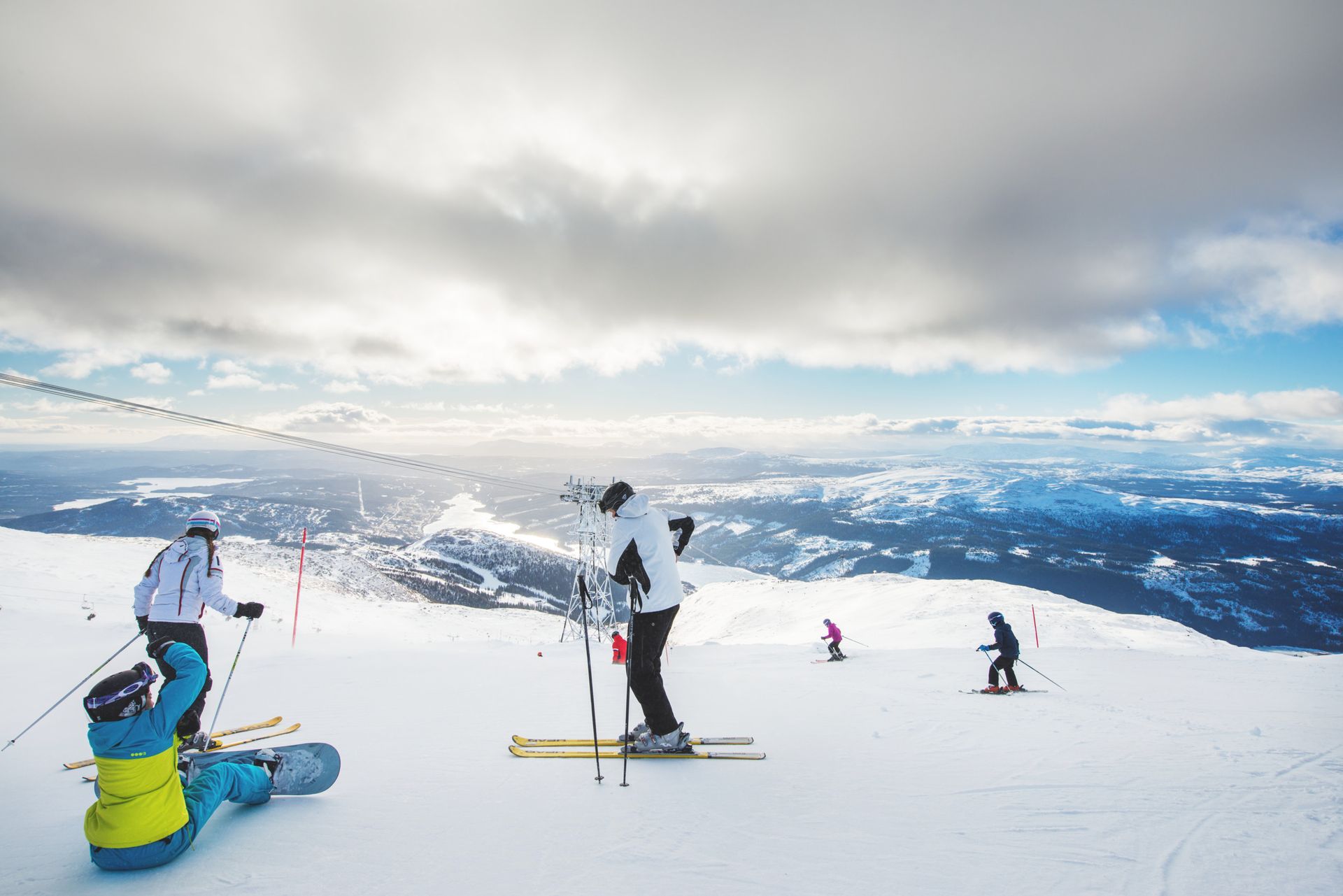 Skiers and snowboarders on a snowy mountain slope with a panoramic view of Åre.