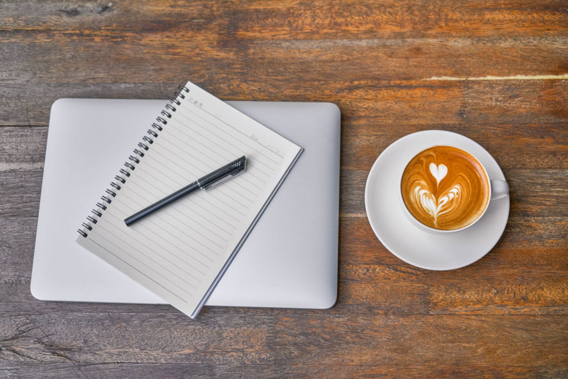 Close-up of a laptop, notebook and coffee.