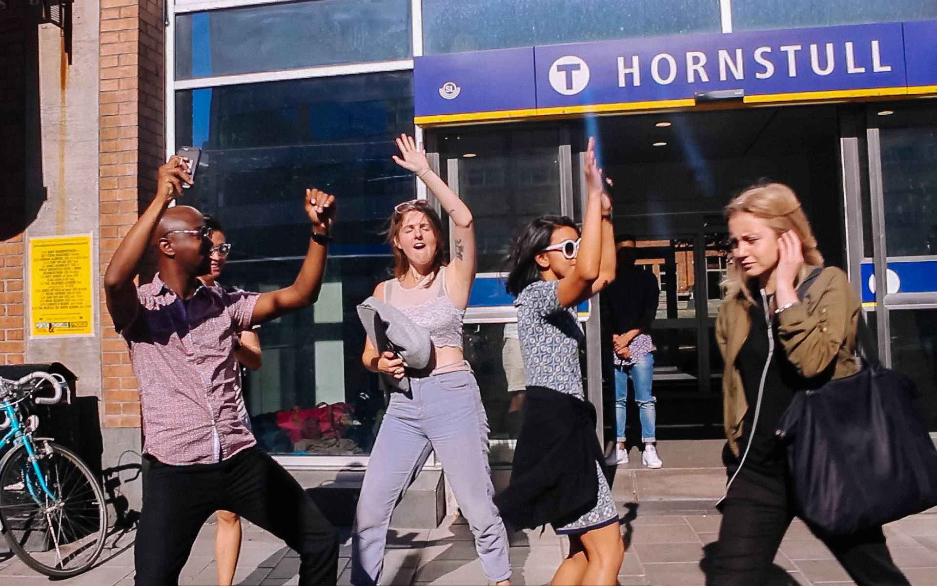 A group of students happily dancing outside a metro station entrance in Stockholm.