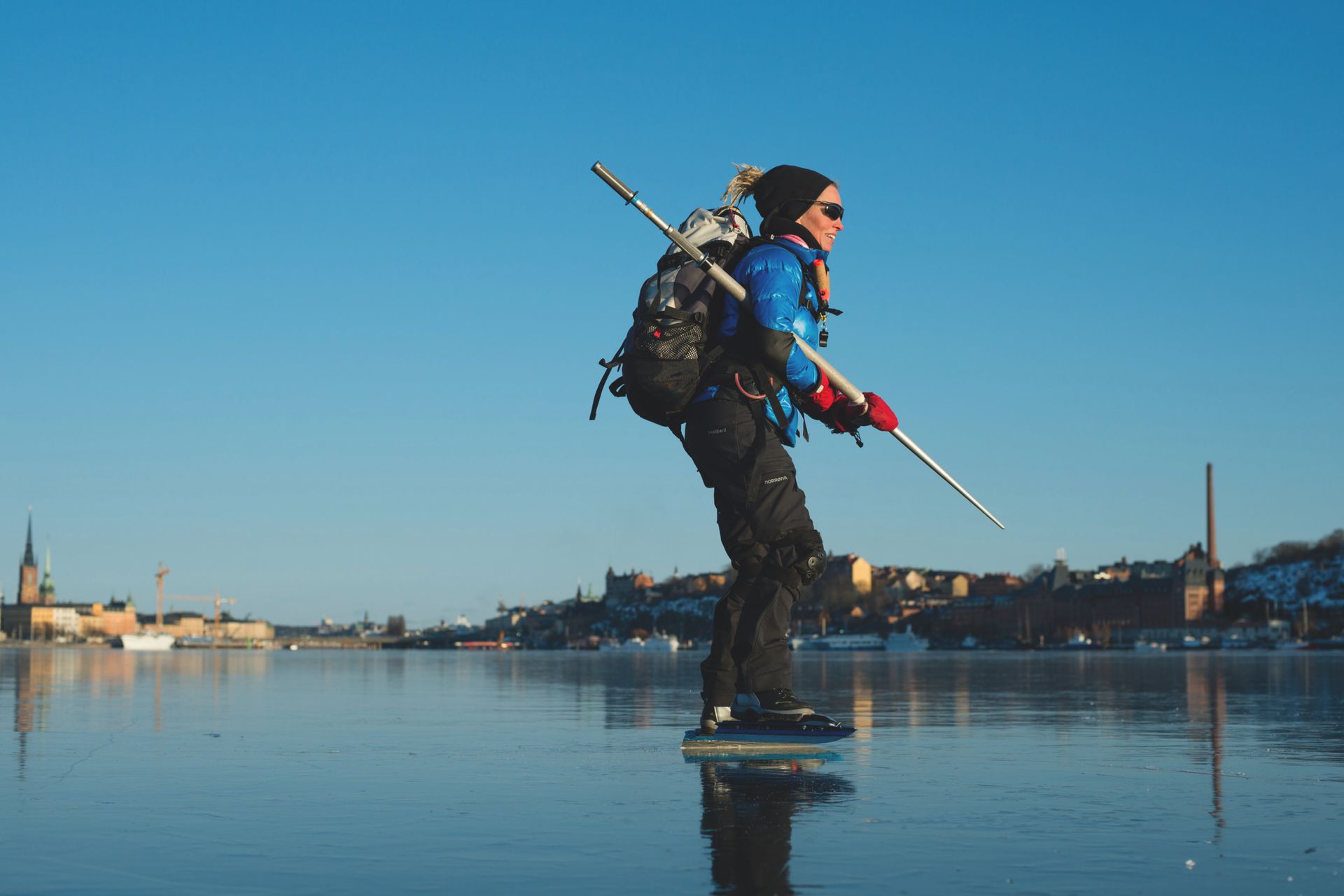 A person skating on a frozen lake with the city of Stockholm in the background.