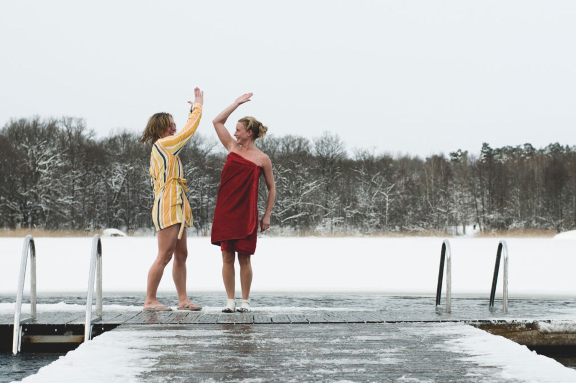 Two people standing on a snow covered jetty.