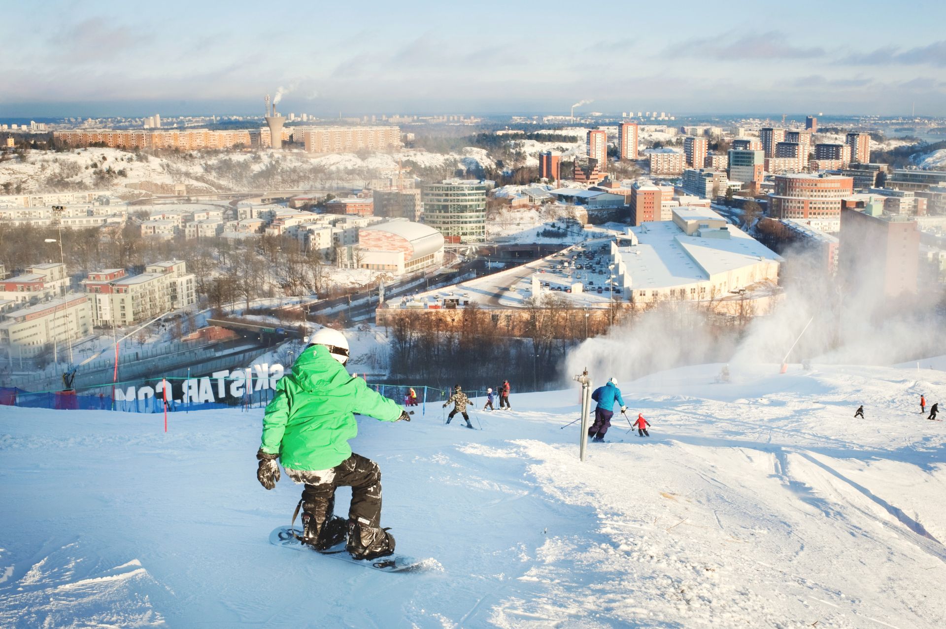 Skiers and snowboarders on a ski hill overlooking Stockholm.