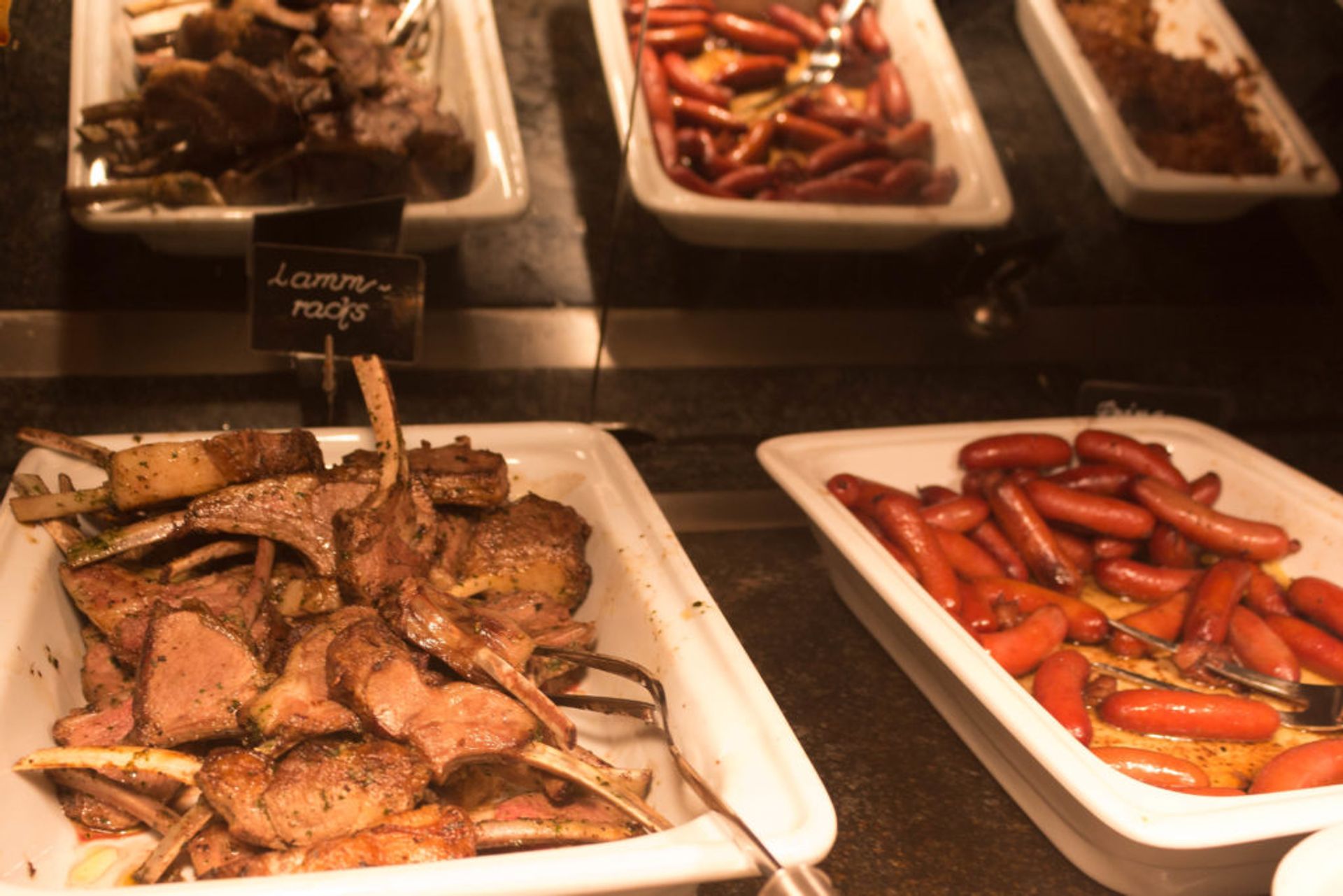 Close-up of plates of lamb ribs and sausages.