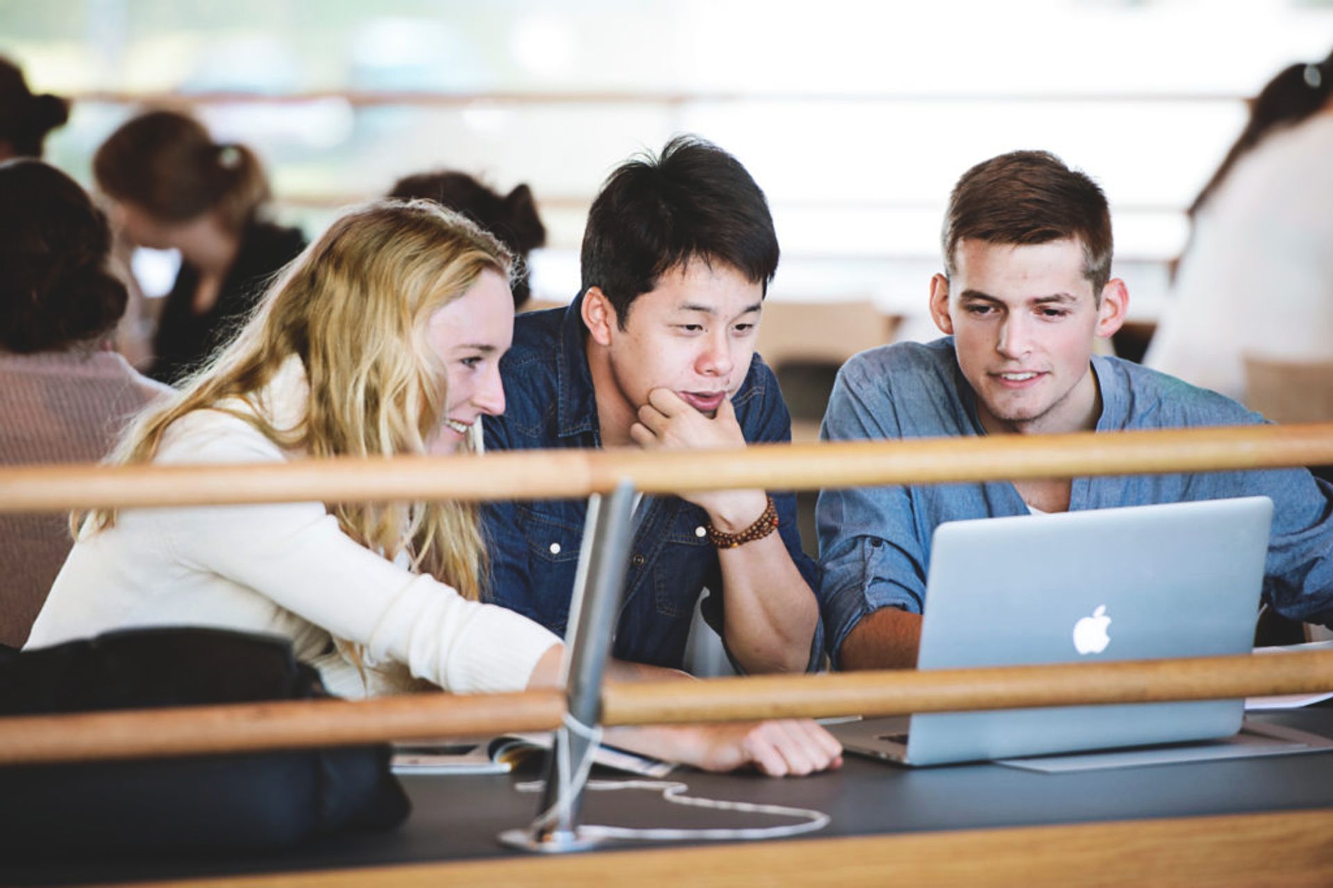 Three international students sit at a Uppsala University campus working on a group project together.