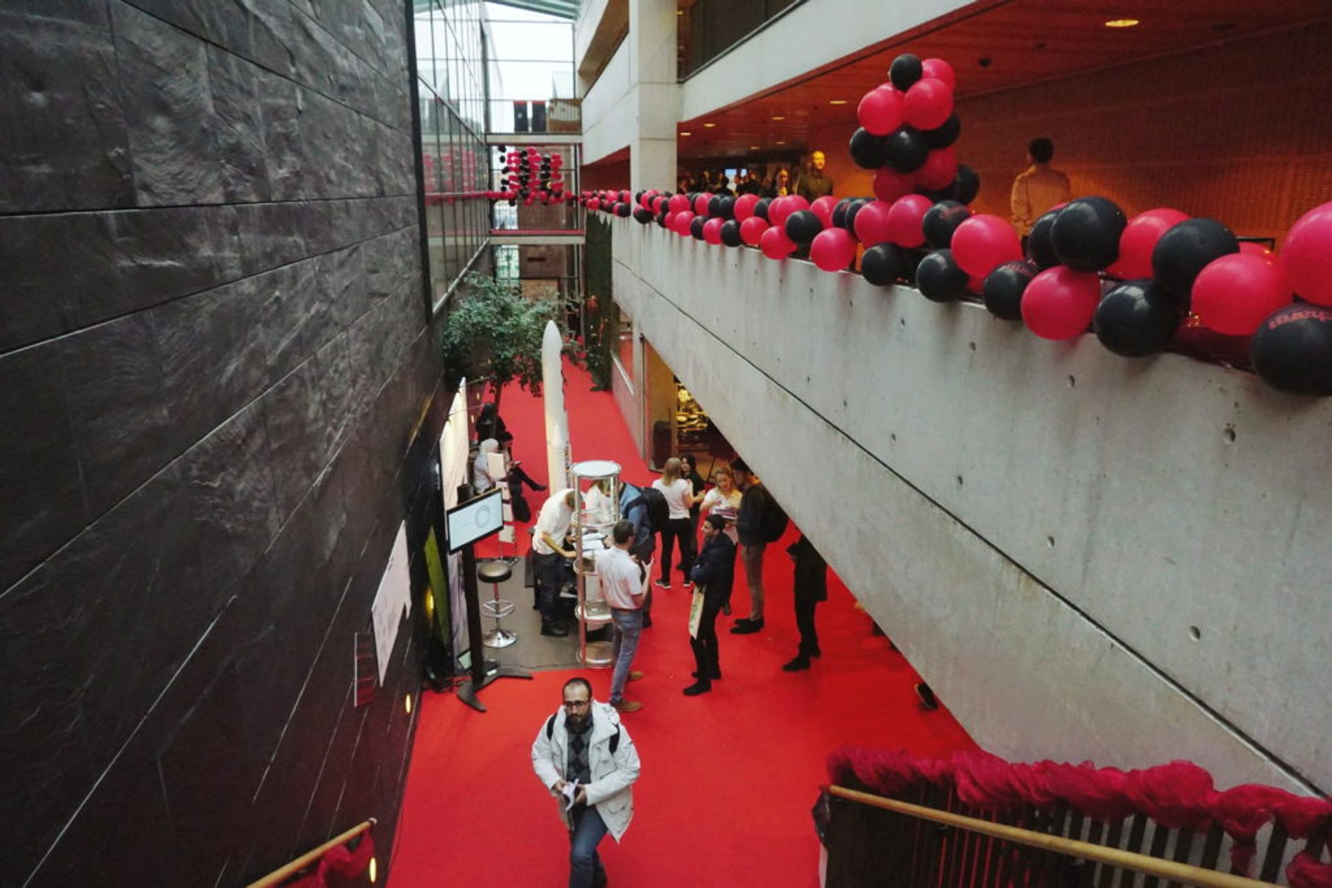 People talking at a booth at the CHARM career fair. You can see decorations with balloons and a red carpe