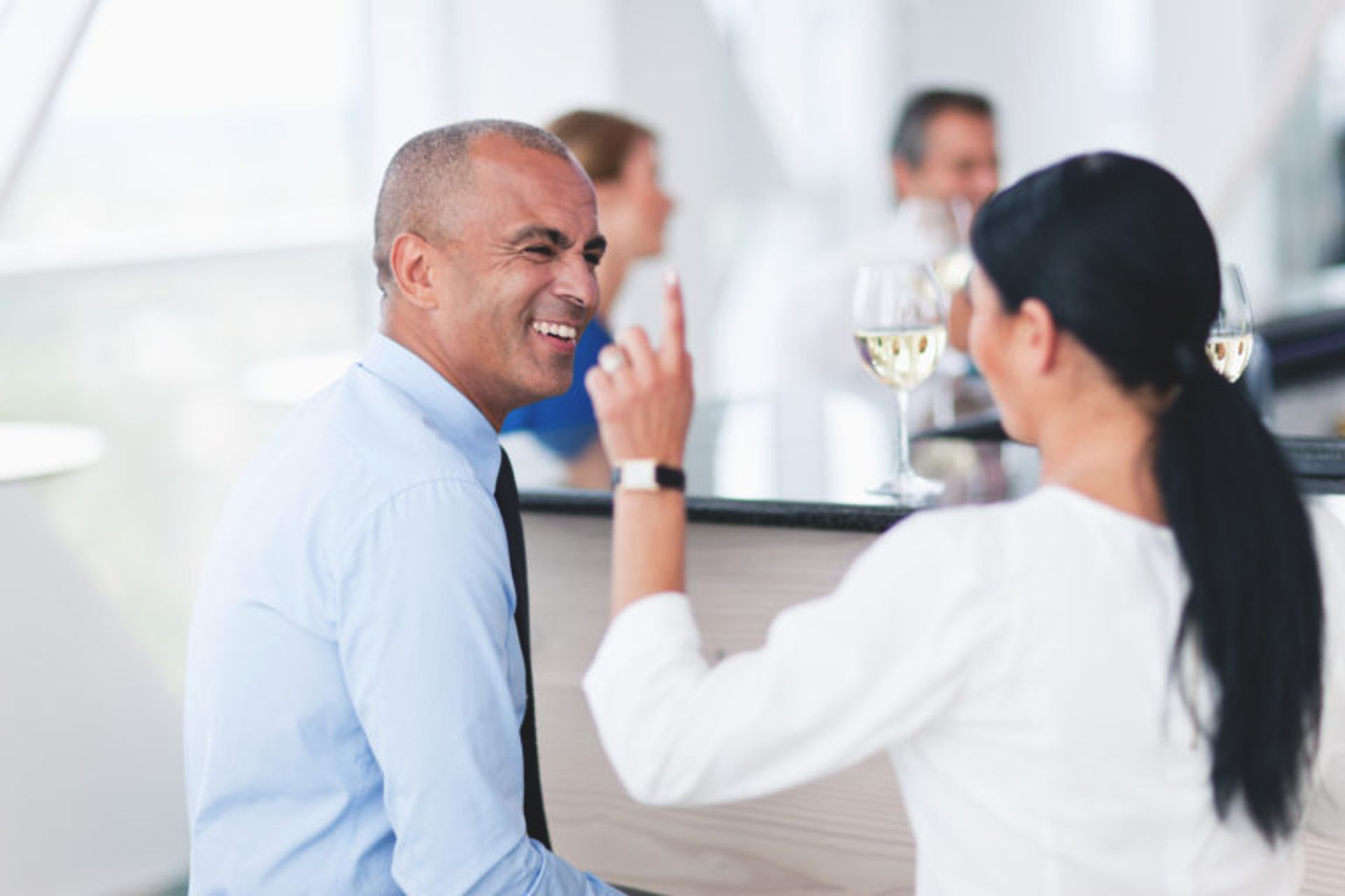 A man smiling at a women who is talking. They are sitting in a bar.