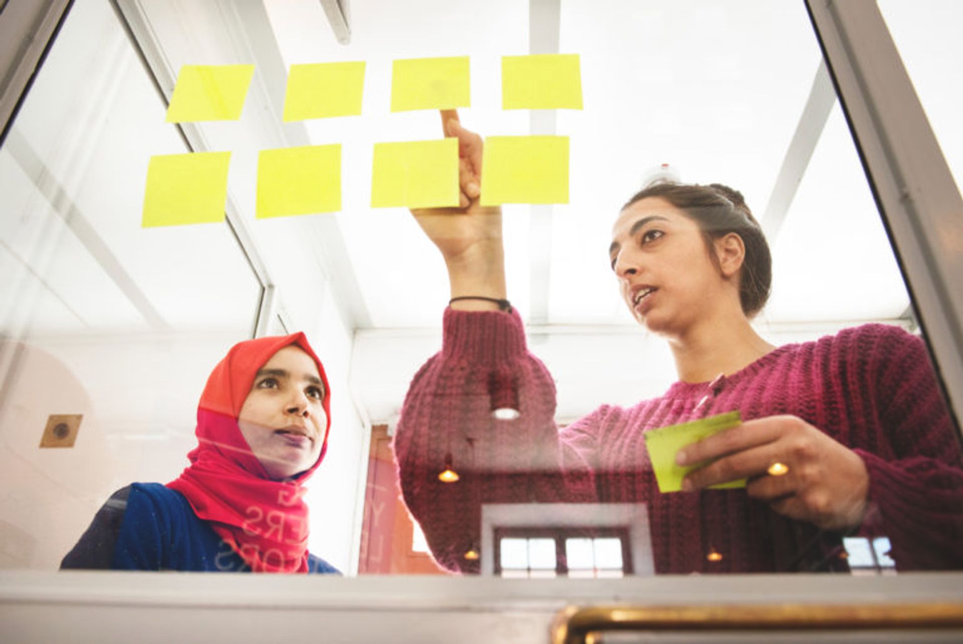 Two students working on a project with yellow post-it notes.