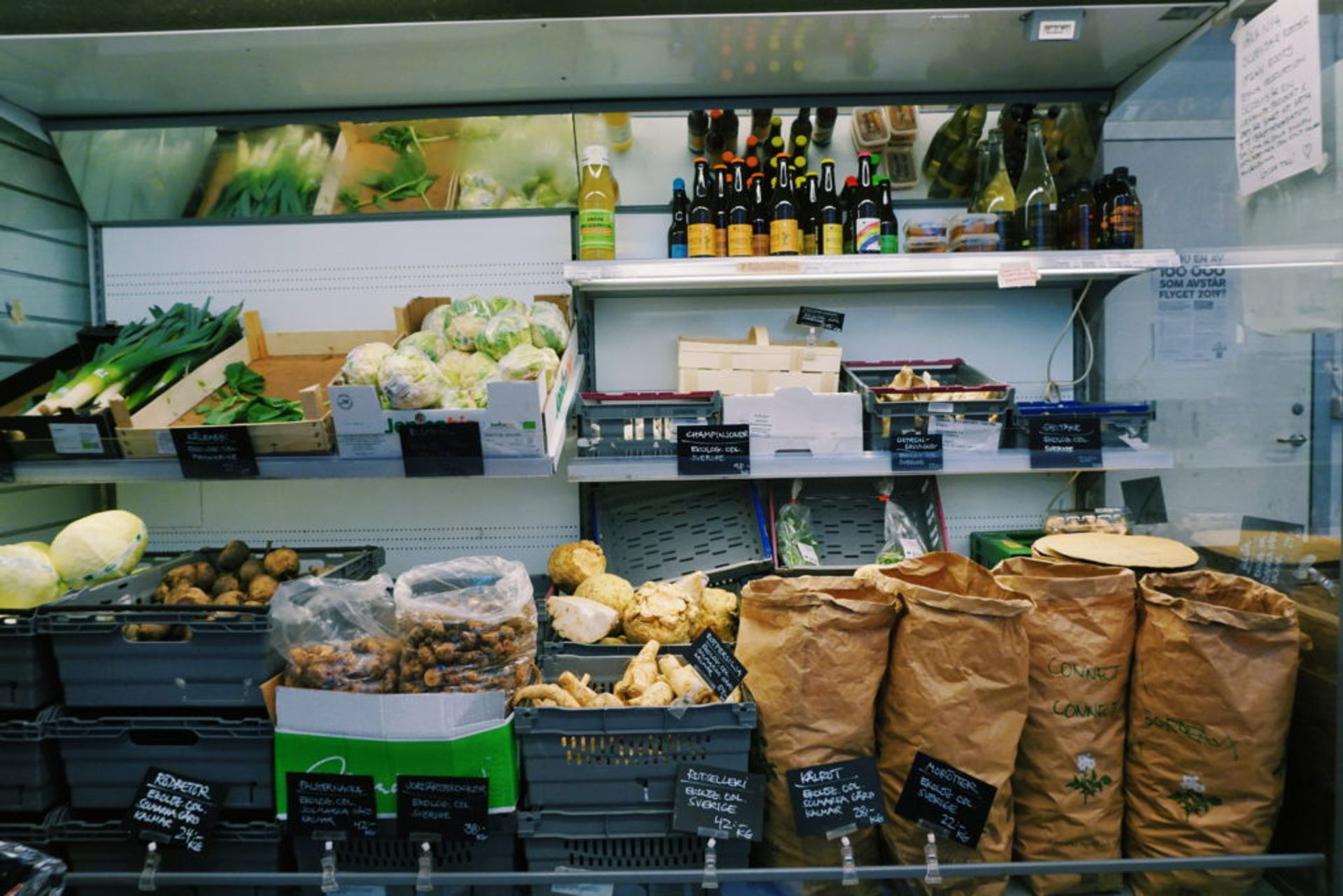 A greens department at a store, including some leek, potato, cabbage and some bottle cans.