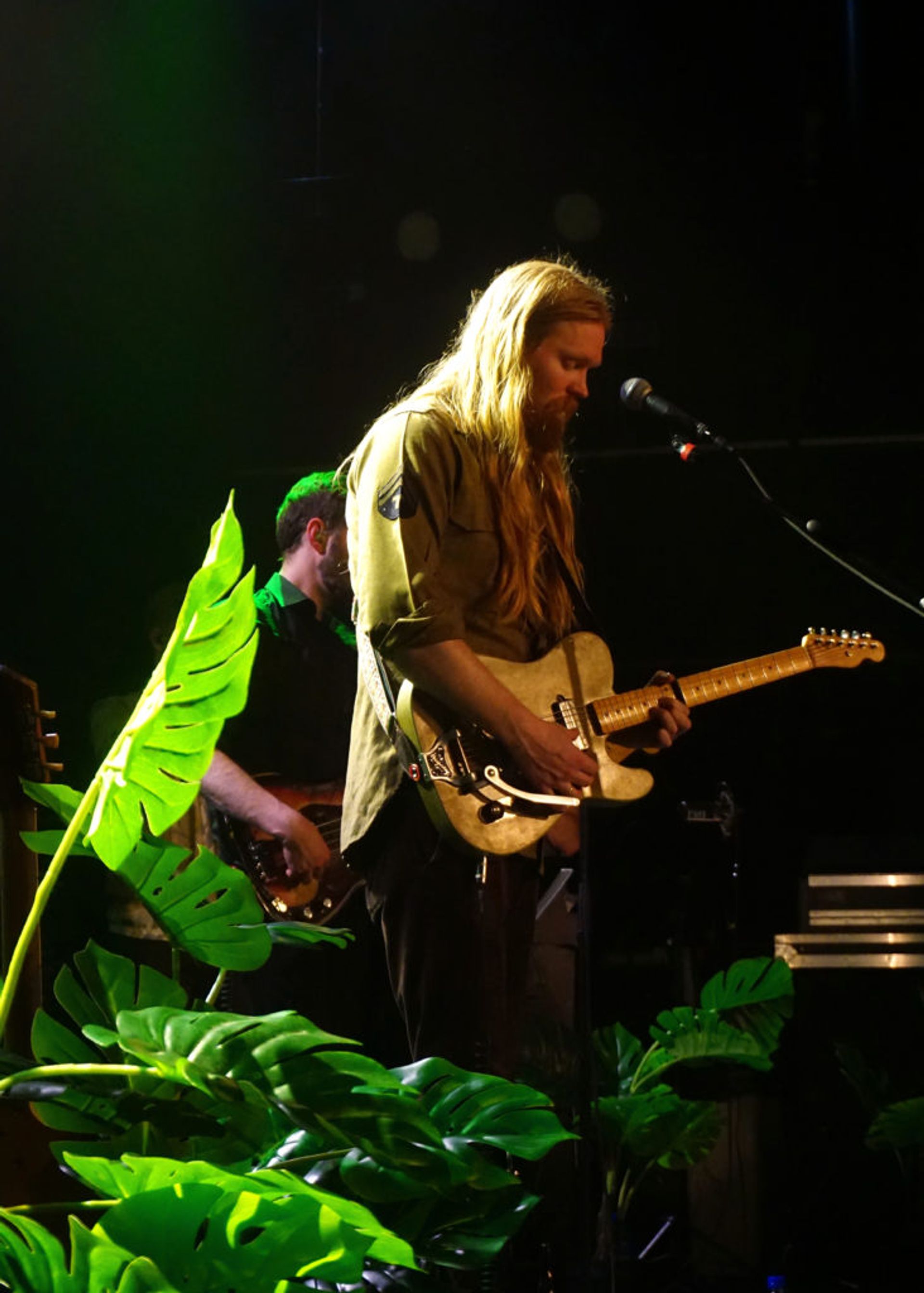 The singer Júníus Meyvant performing on a stage in back light. 