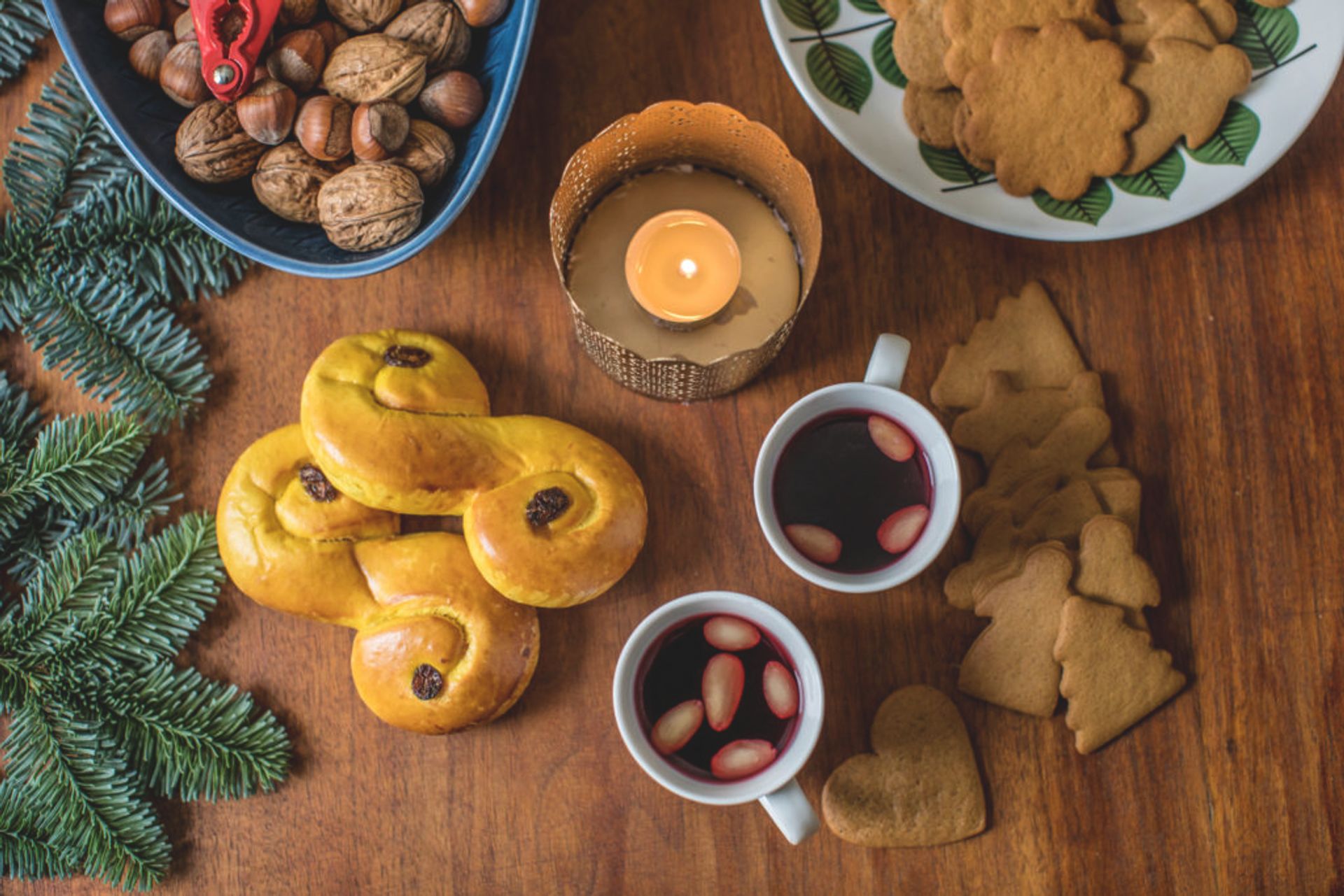 Two cups of mulled wine, saffron buns, ginger bread and Christmas decoration on a table.