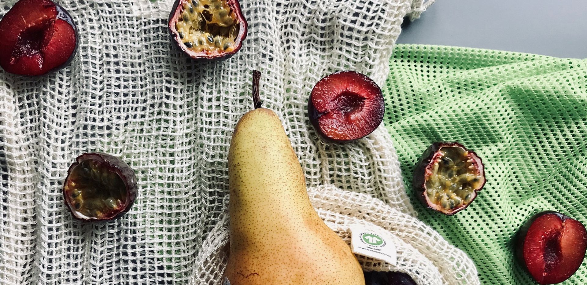 A pear, some passion fruit and cherry halves on a towel.