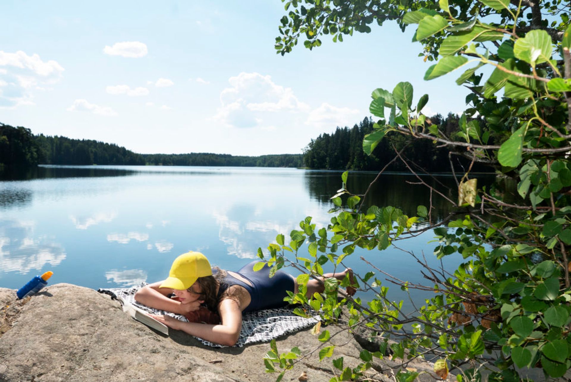 Girl lying on a hillside while sunbathing and reading a book.