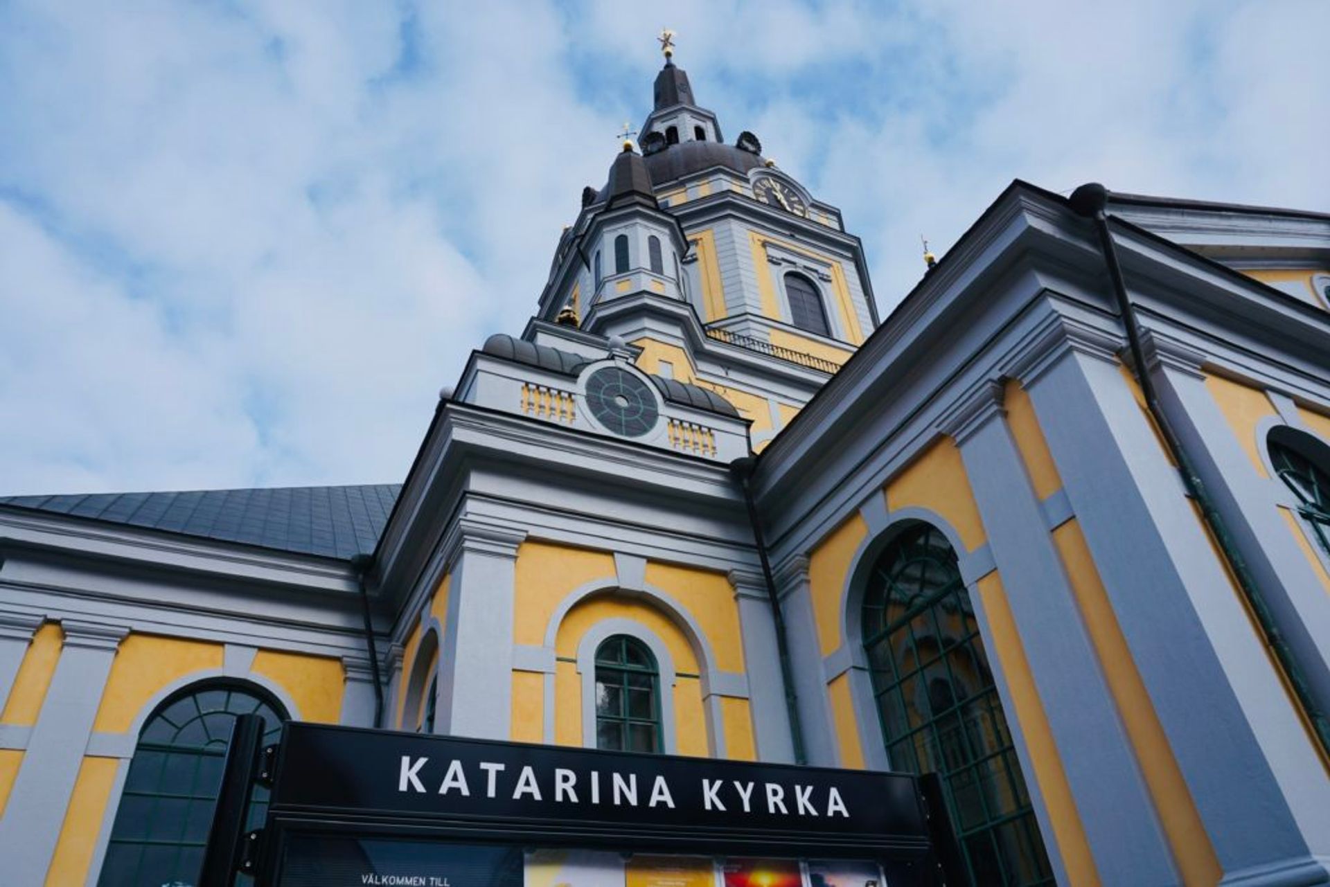 Exterior of a yellow church, sign reads 'Katarina kyrka'.