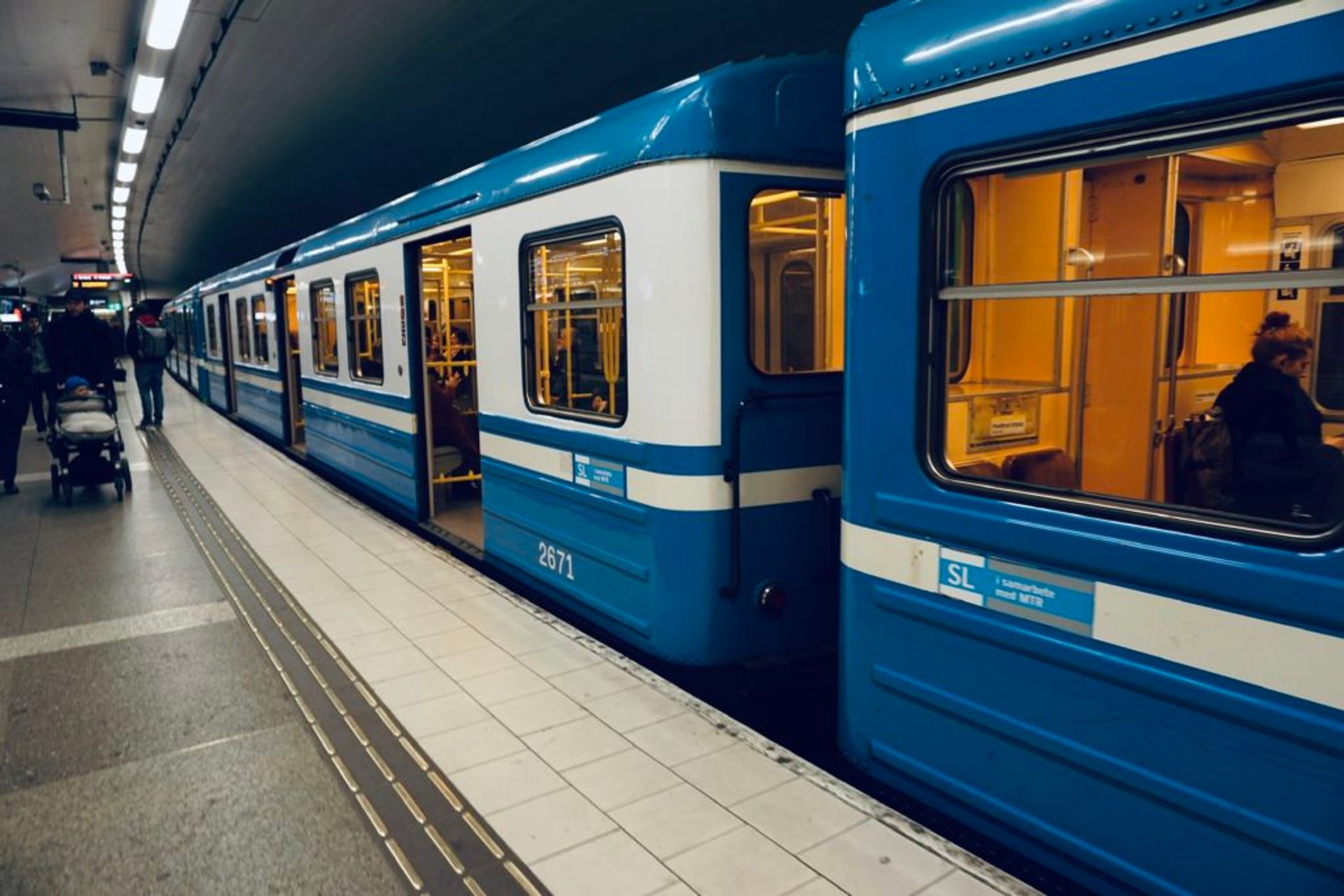 Blue metro trains waiting at a metro station.