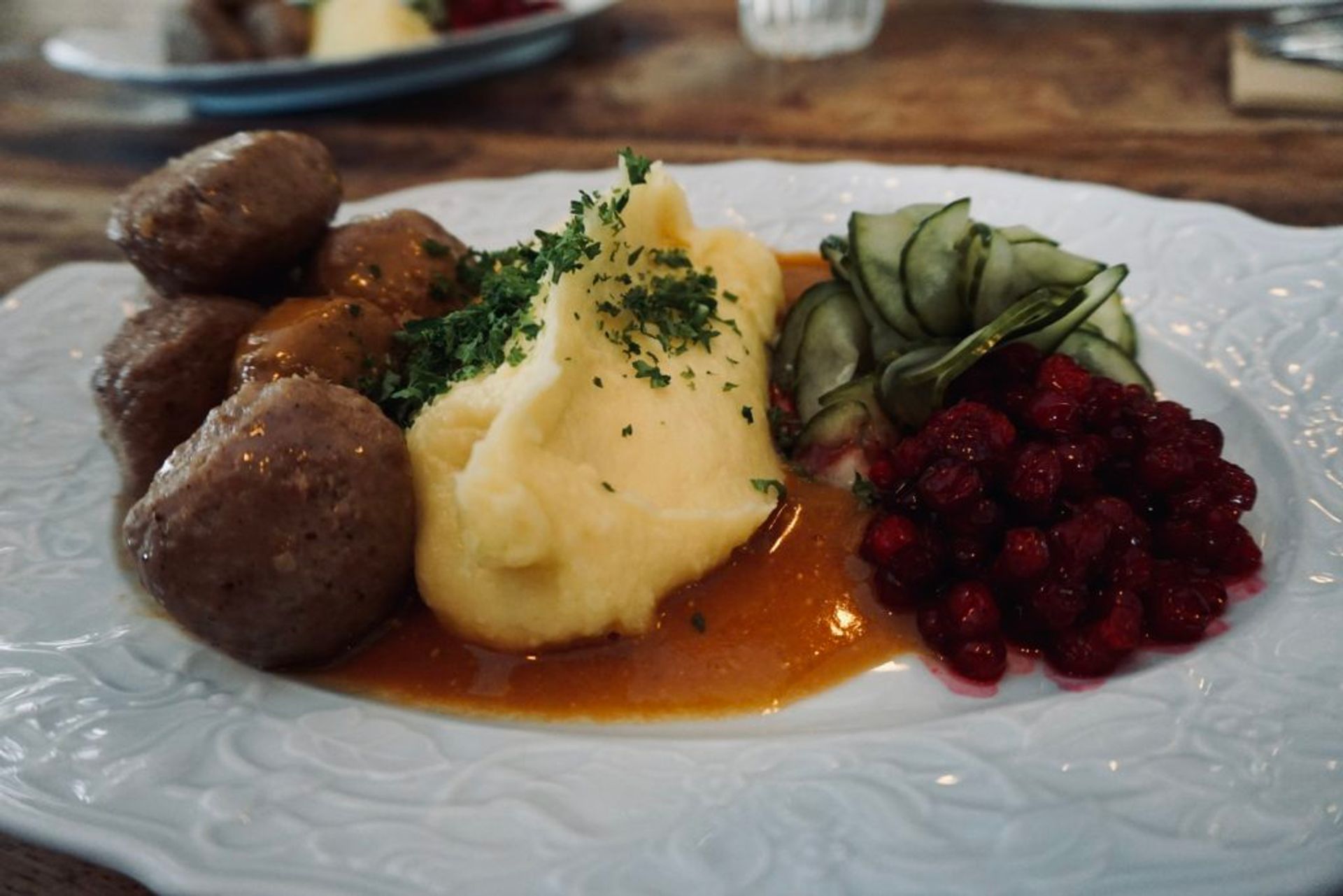 Close-up of meatballs served with potatoes, lingonberry jam and gravy.