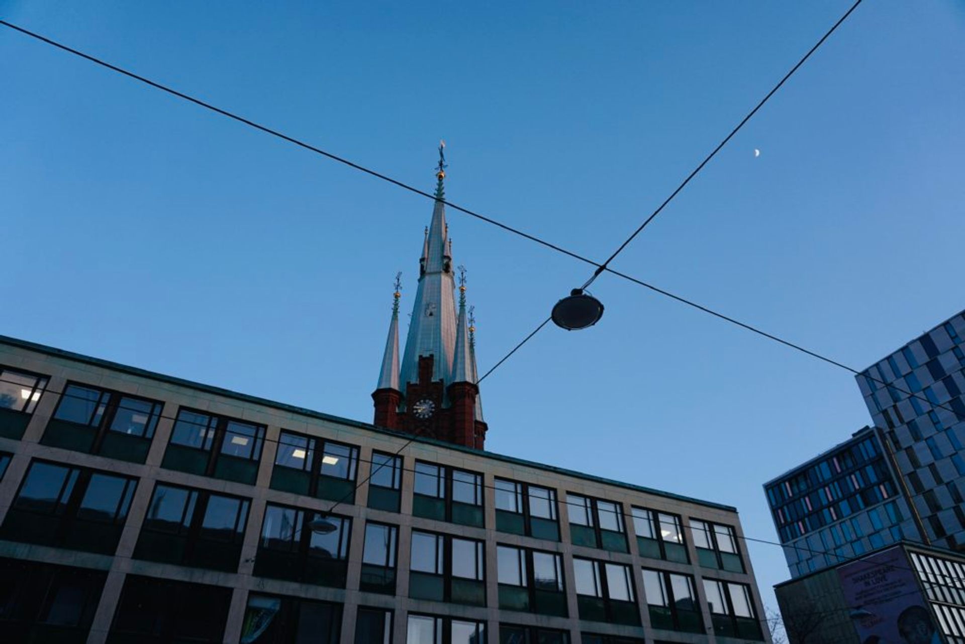 A church spire towers abover an office building.