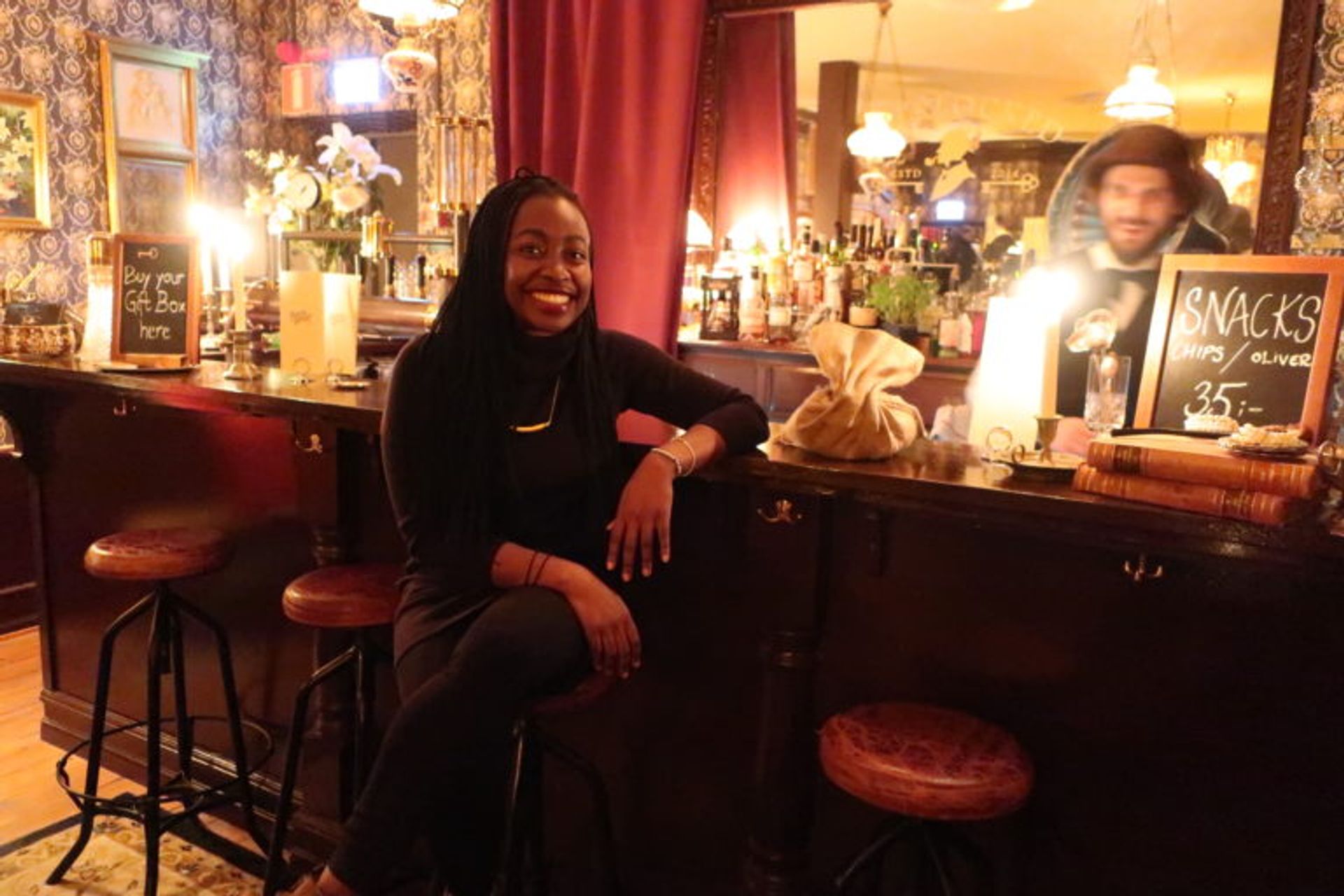 A woman sitting in a bar, she is smiling and look very happy.