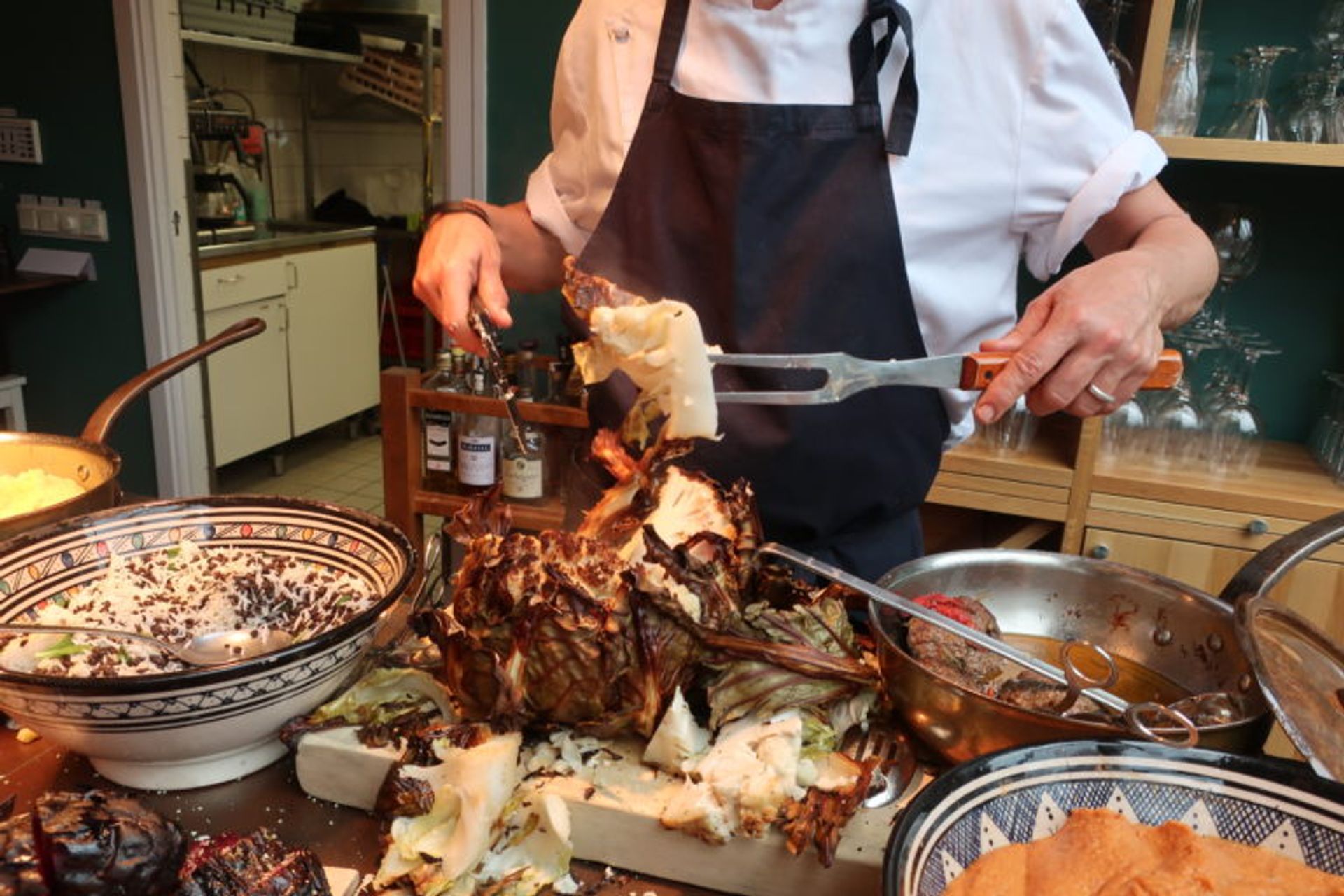 A close up of food a chef is preparing. It is some kind of meat, some rice and some vegetables.