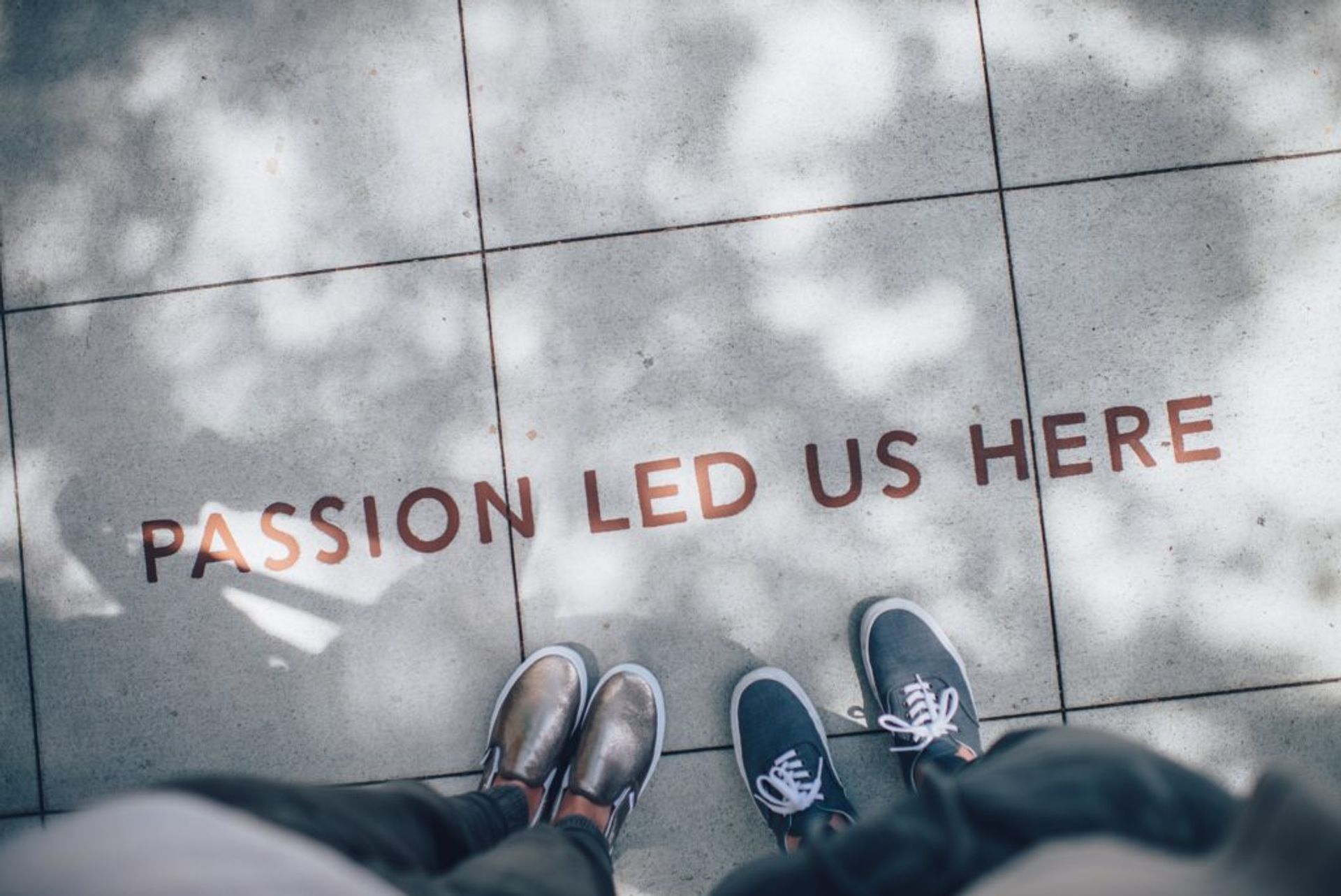 People standing on a sidewalk, the text on the sidewalk reads 'Passion led us here'.