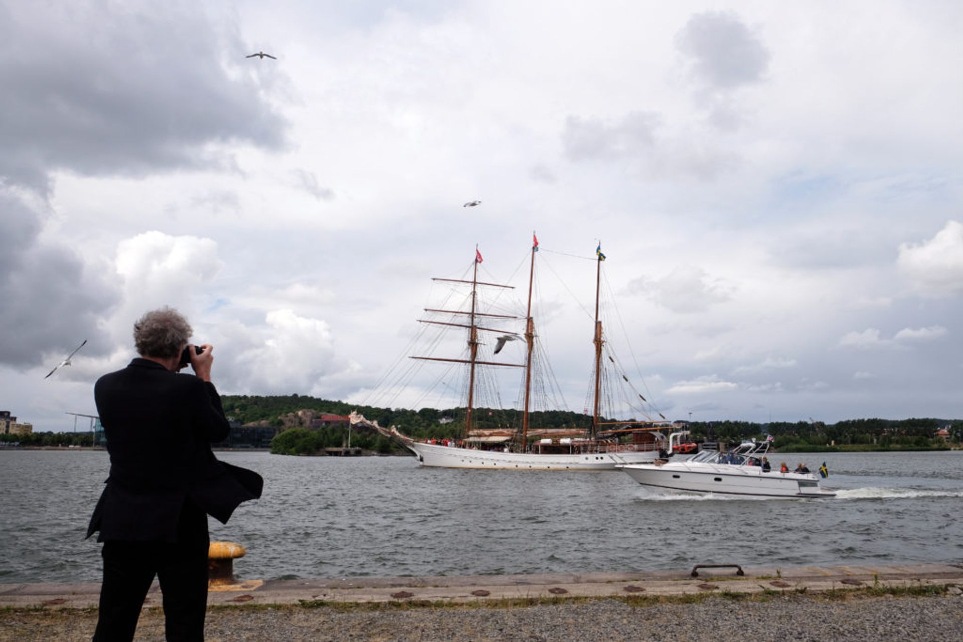 Person standing at the docks, taking photos of boats.