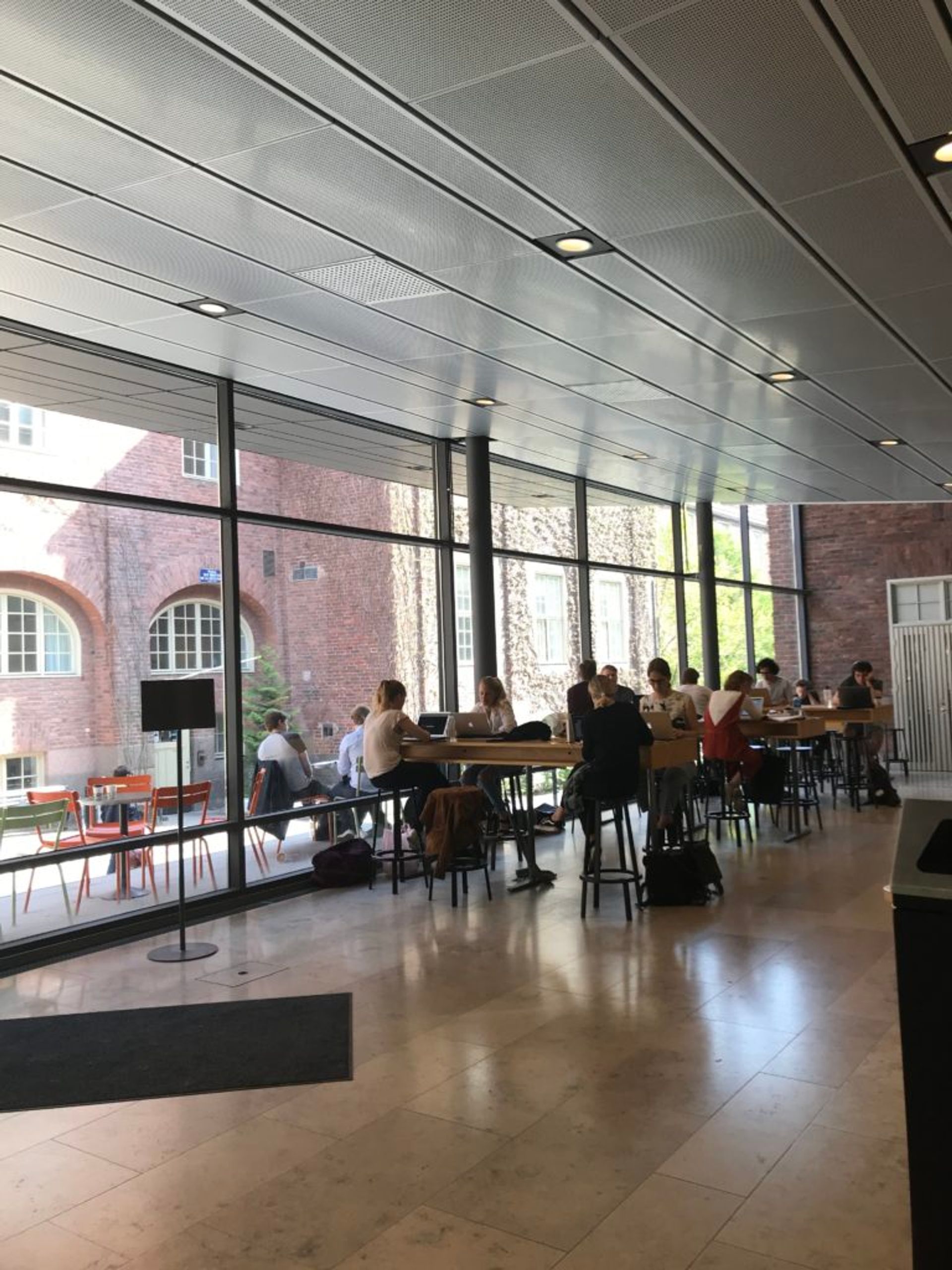 Students eating lunch and studying at tables inside.
