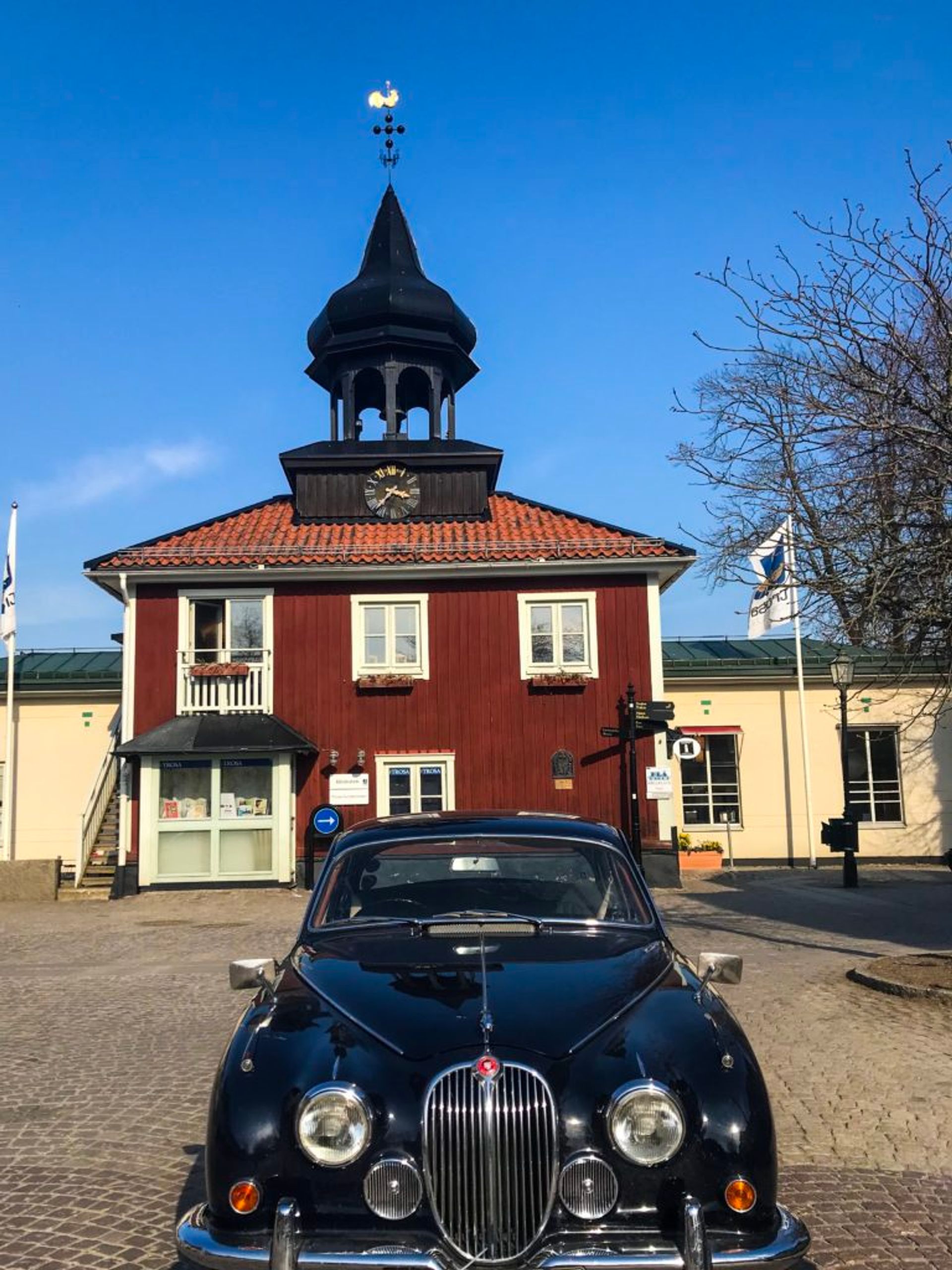 An old-fashioned car parked in front of a red building.