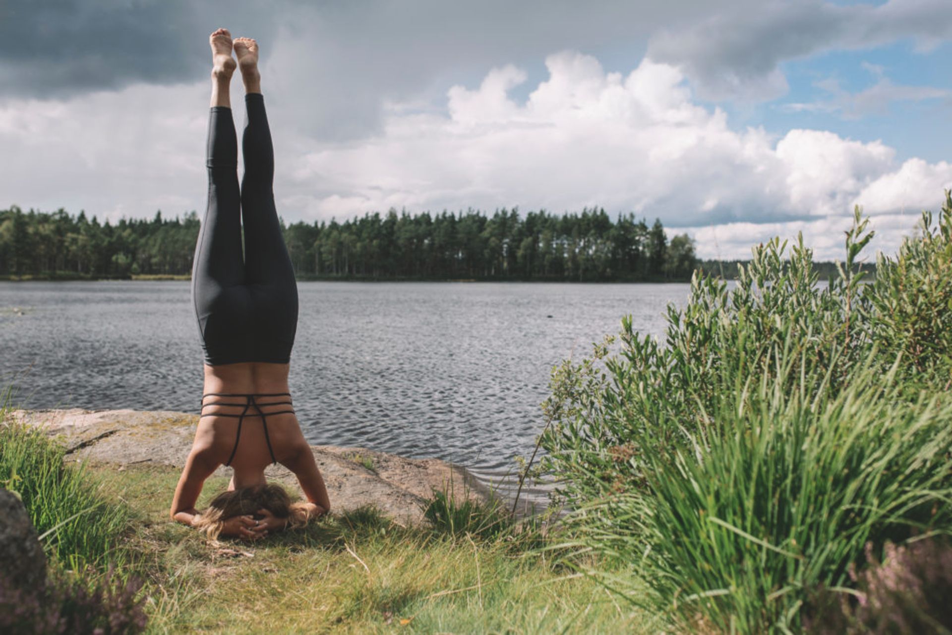 A woman doing yoga beside a lake.