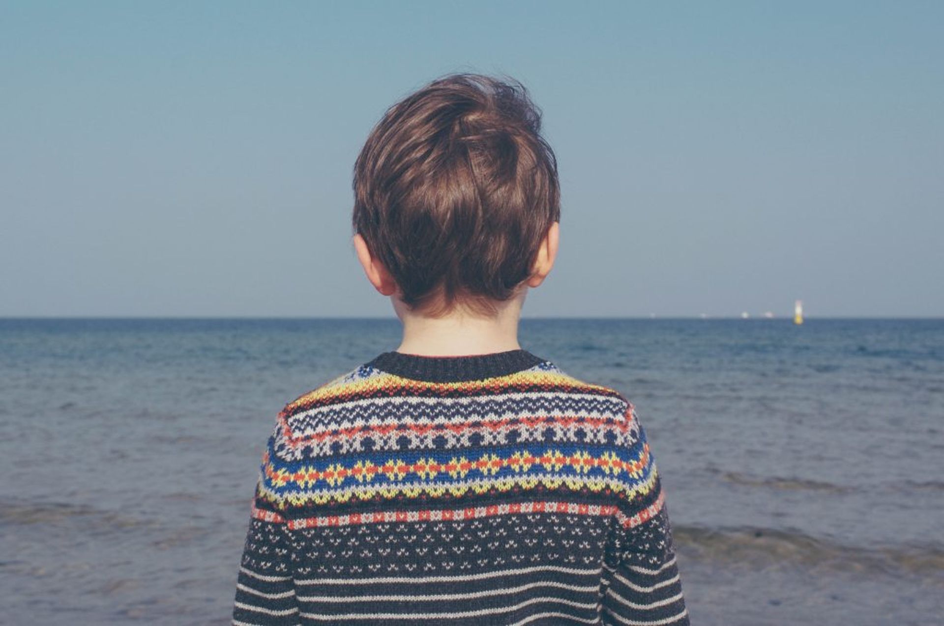 Close-up of a child looking at the ocean.