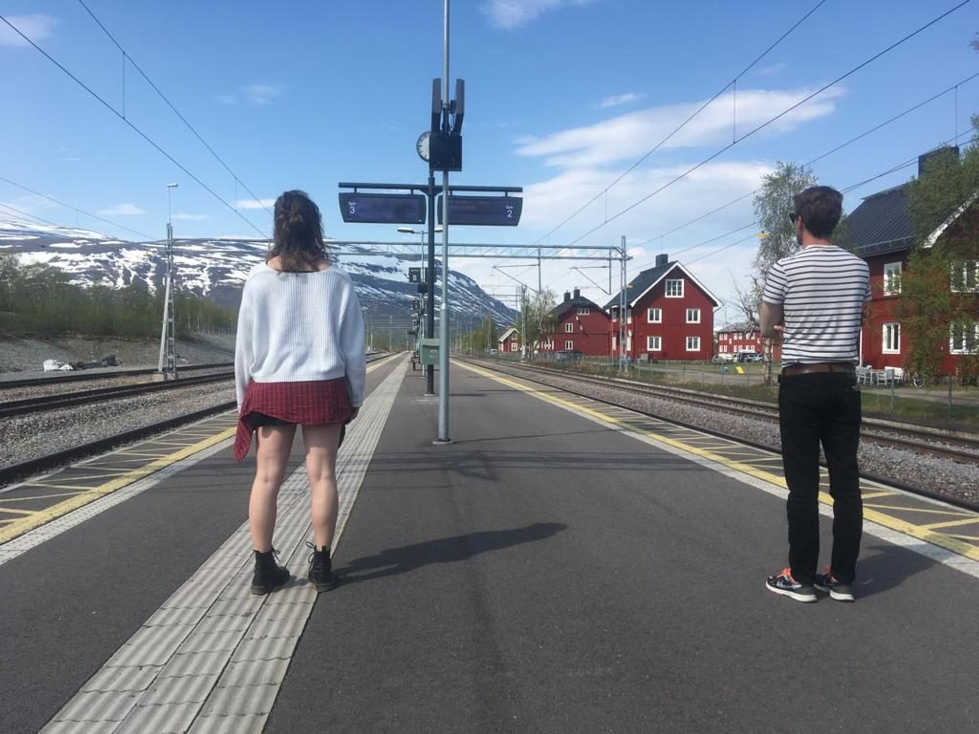 Two students standing on a train platform.