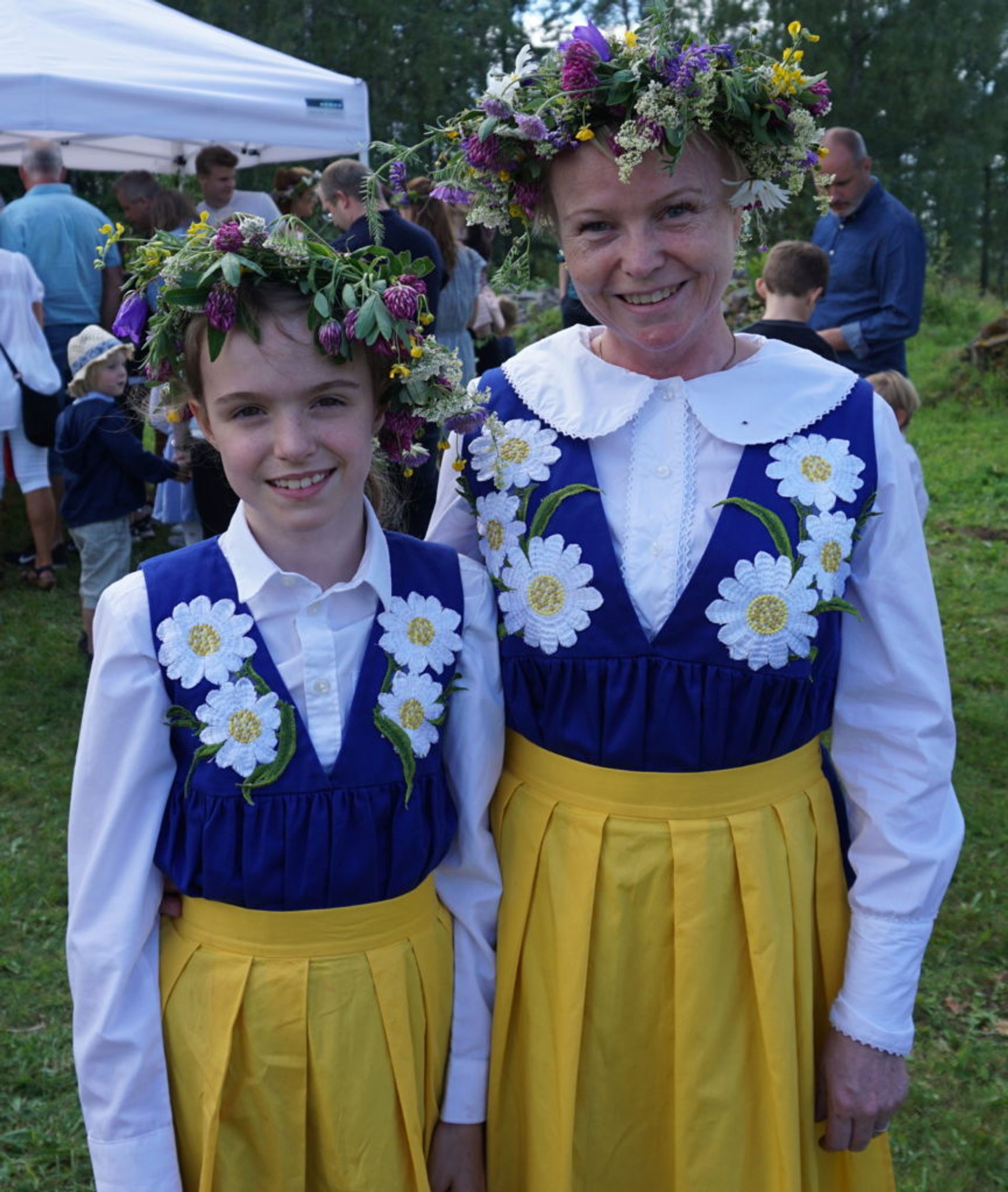 A mother and daughter wearing traditional folk costumes and flower crowns.