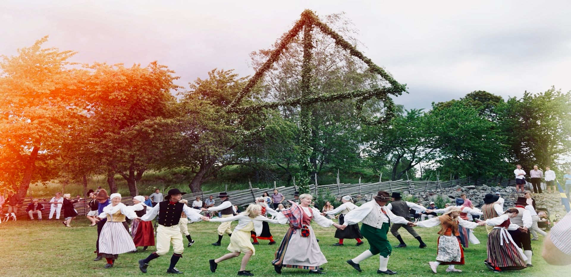 People dressed in folk costumes dancing around a maypole.