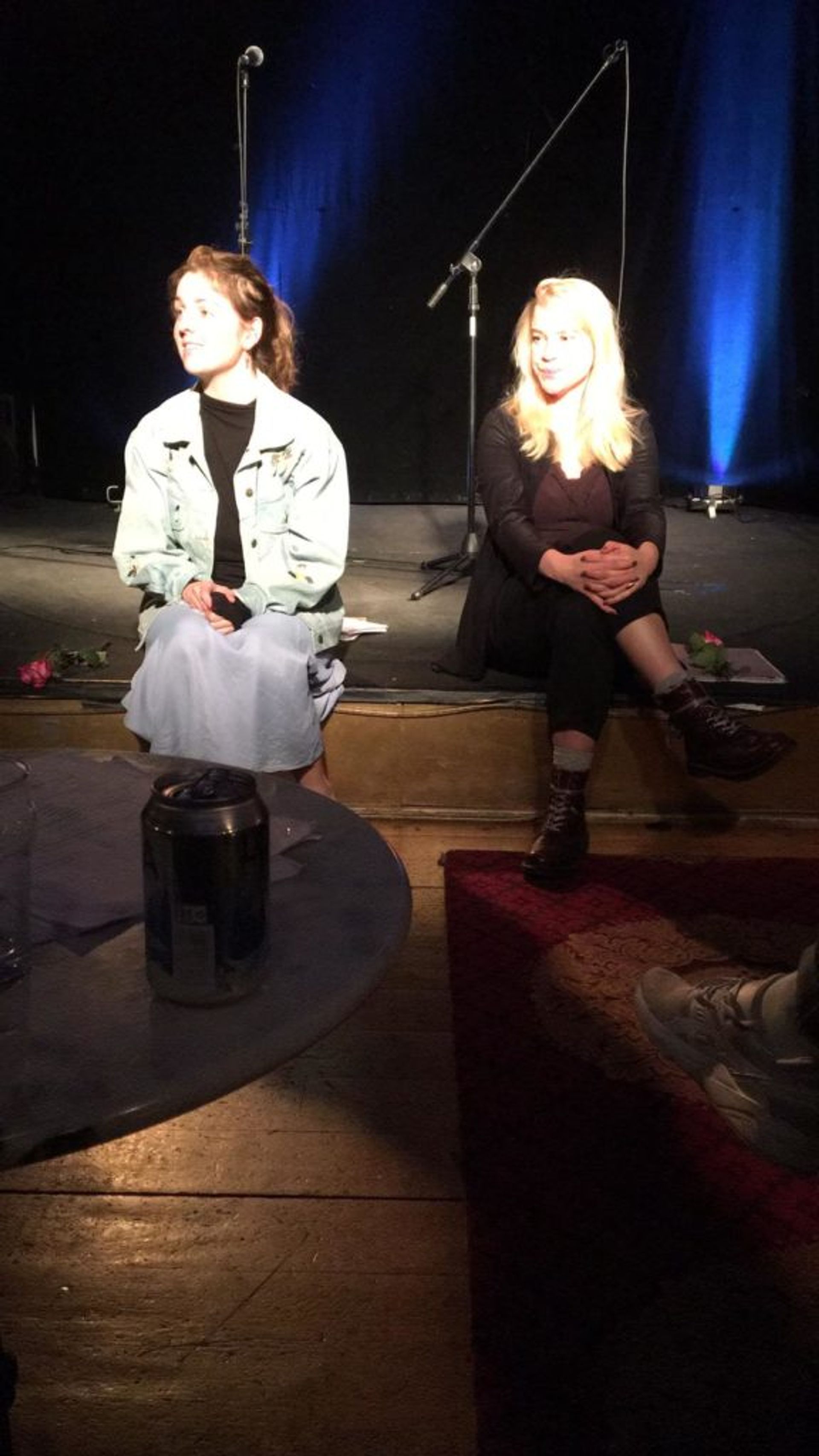 Two students sitting on a stage.