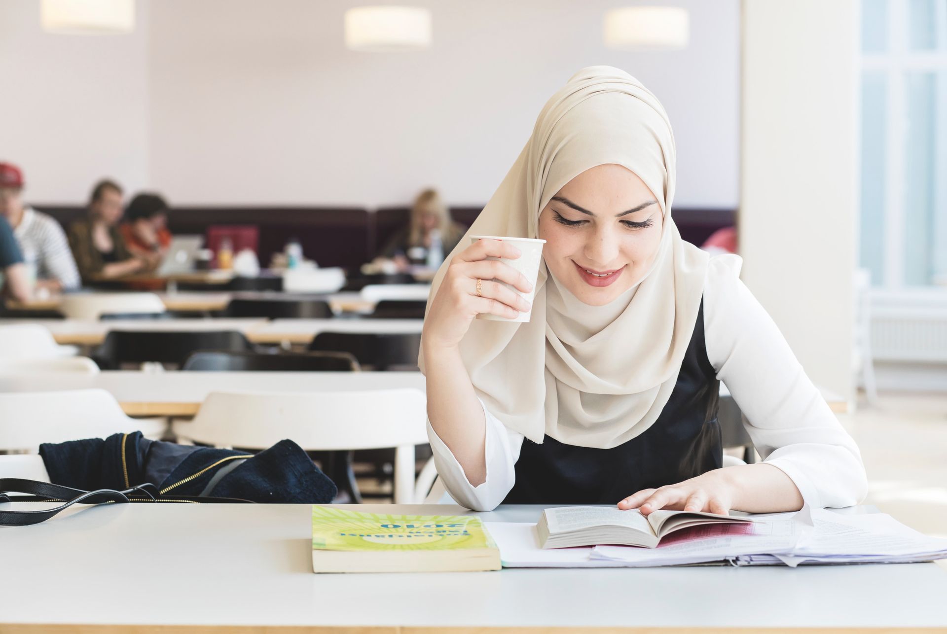 A student at the University of Gothenburg studies while drinking a cup of coffee.