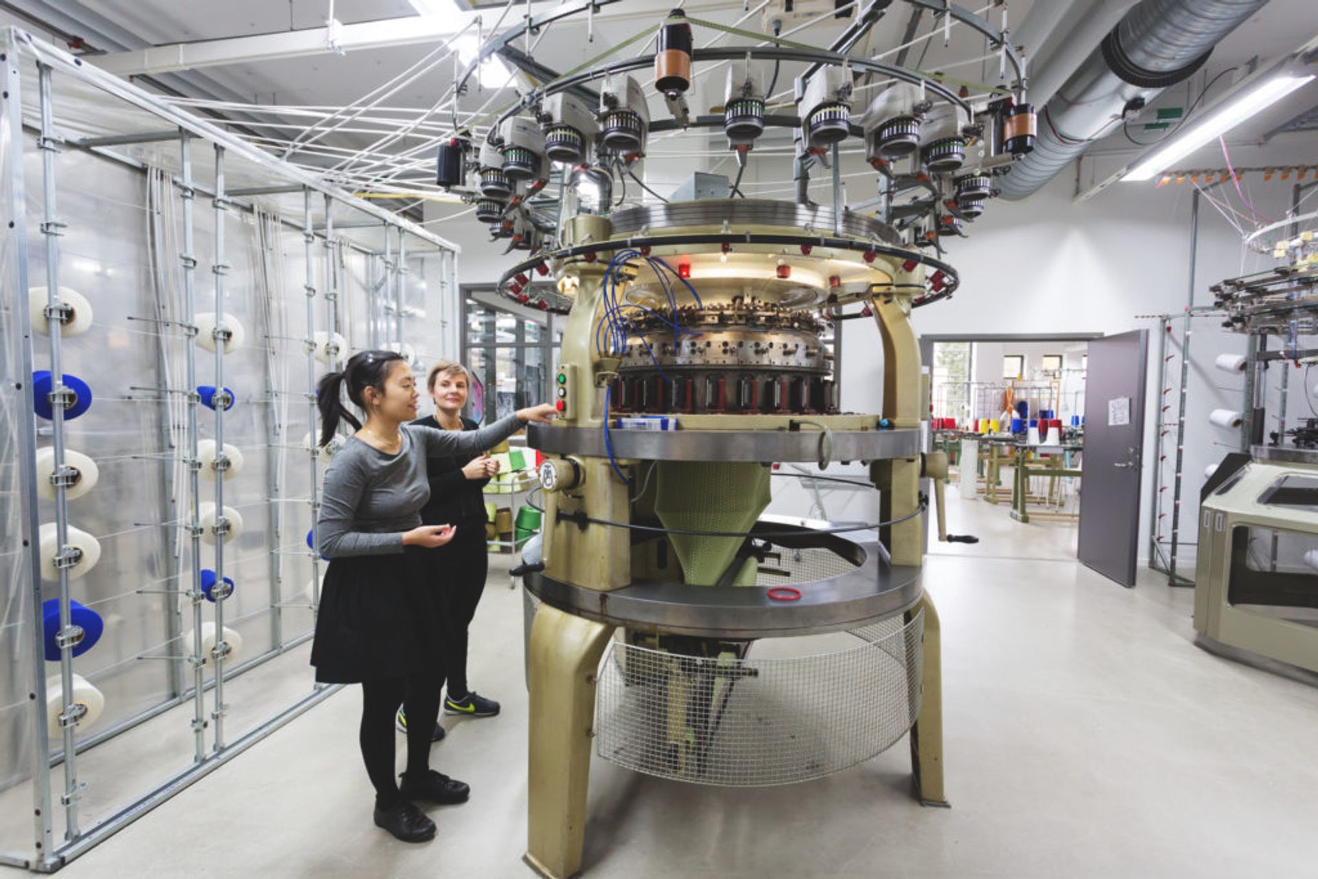 Students standing by a textile machine..