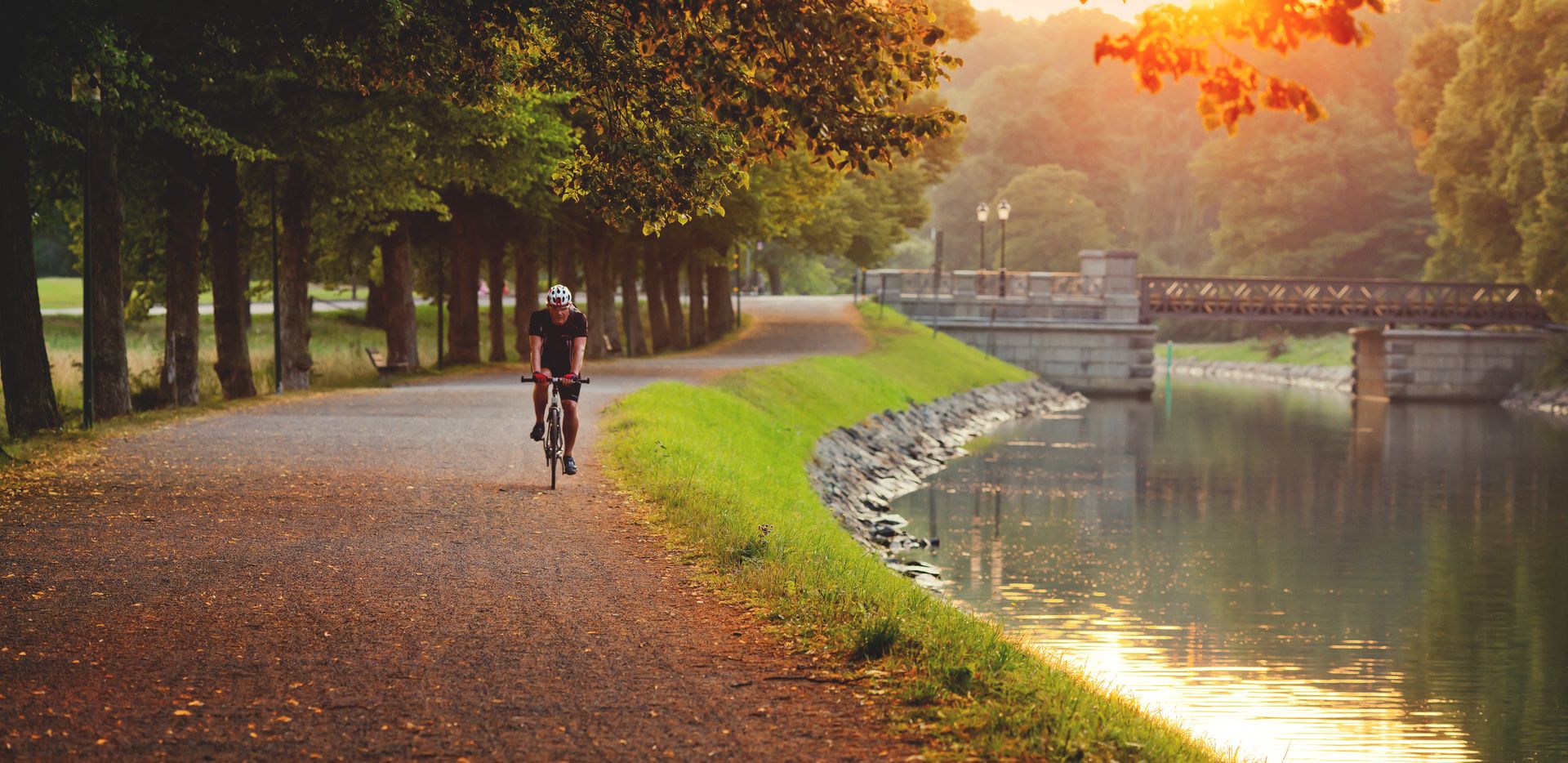 Person cycling along a path beside a canal.