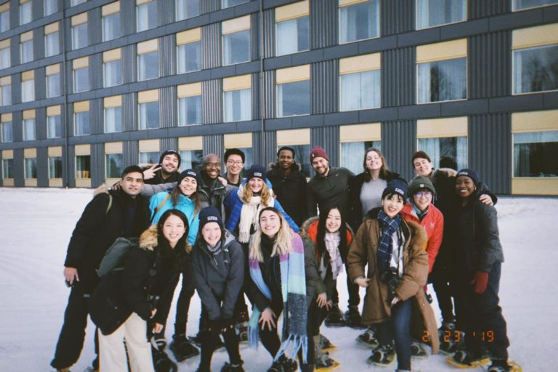 A large group of students pose in front of a hotel.