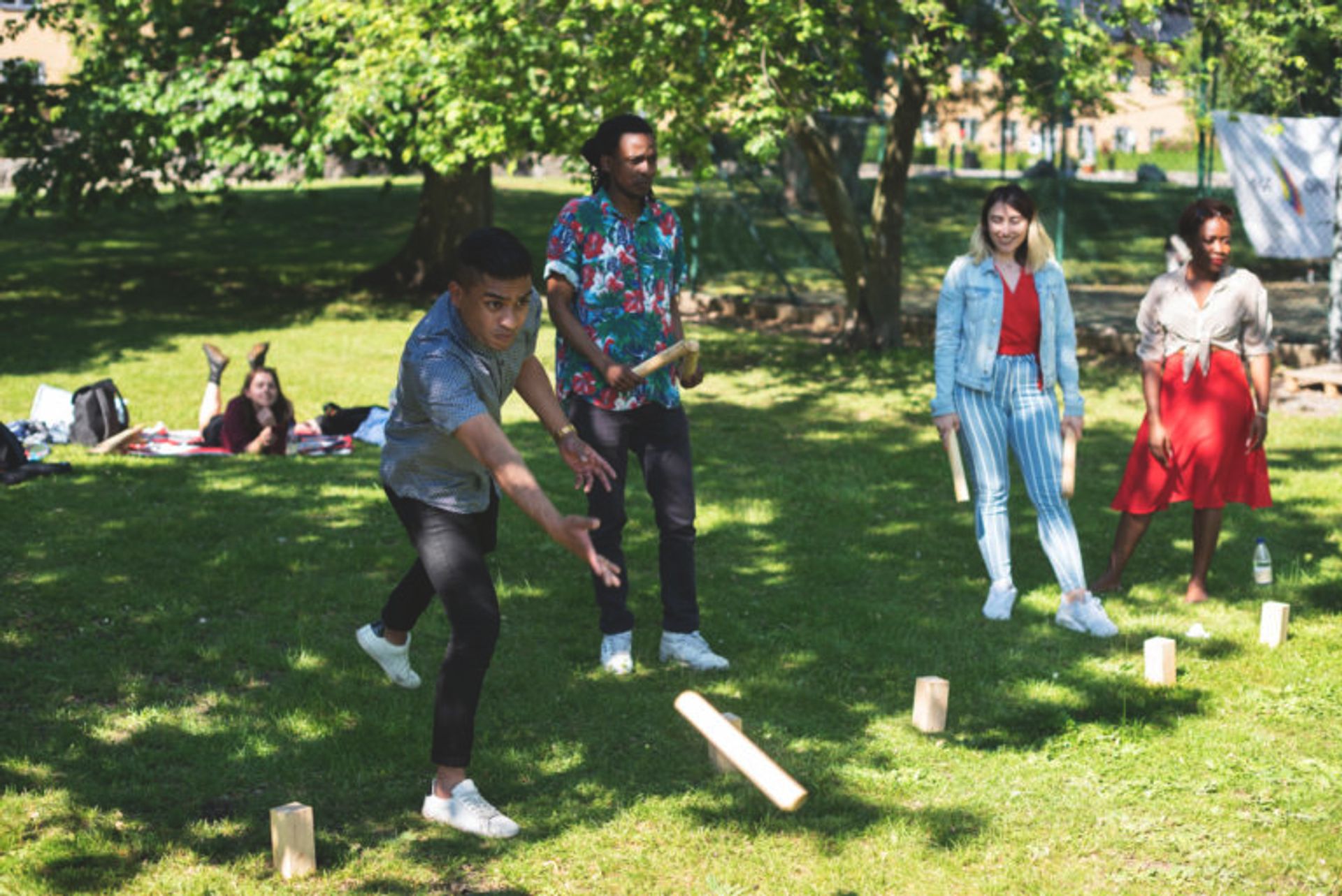 Students playing the Swedish game 'Kubb' in a park.