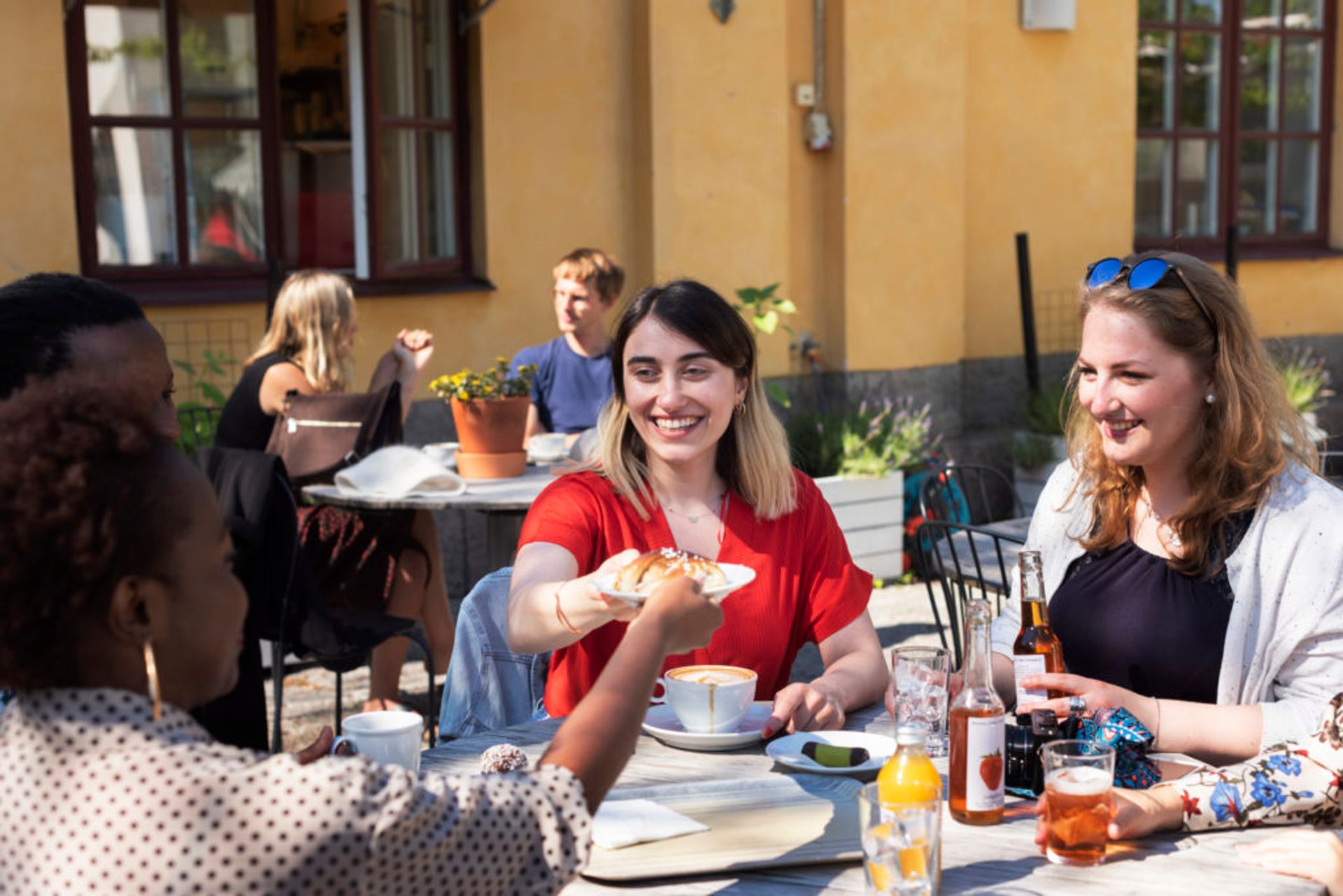 Students sitting at an outdoors cafe drinking coffee.