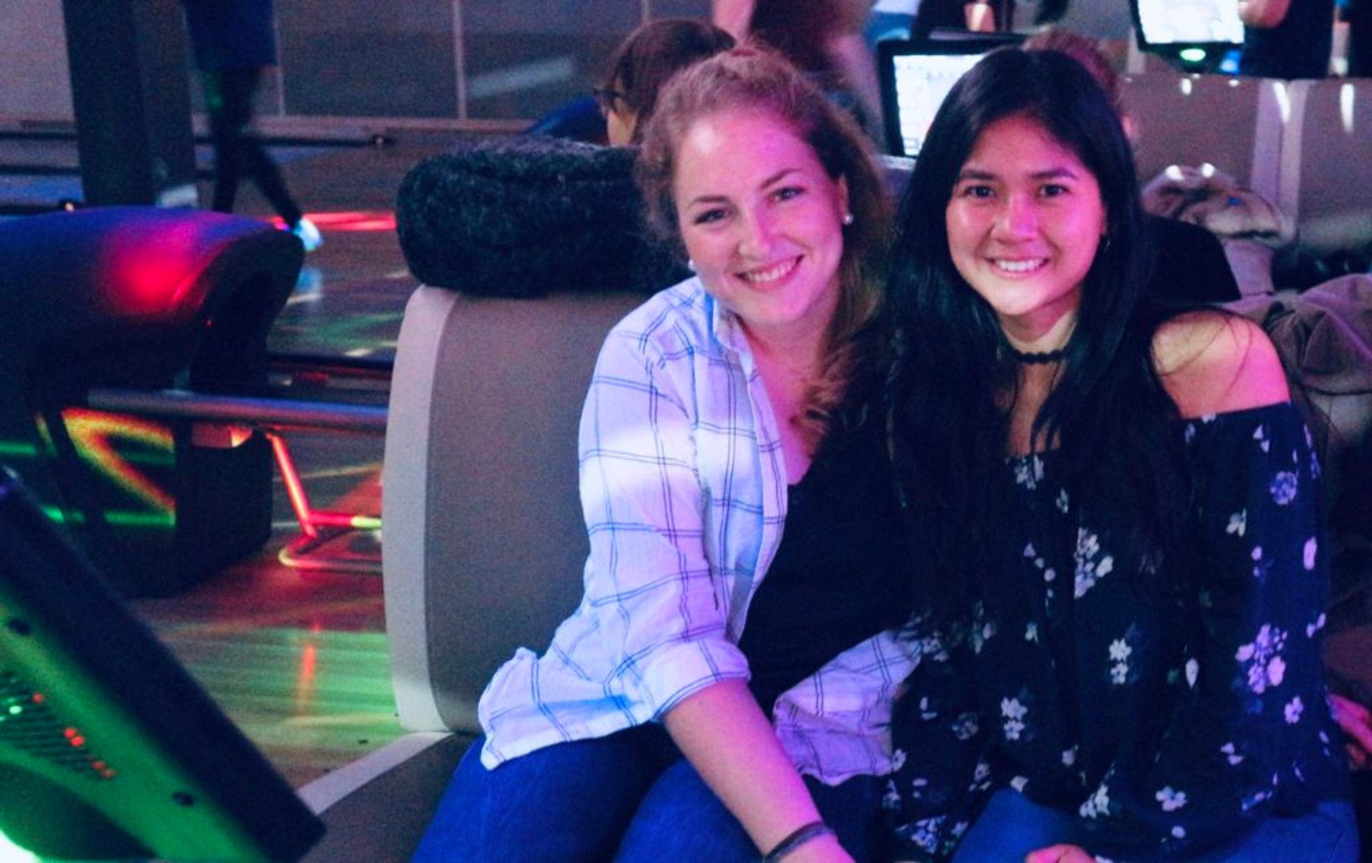 Two students sit together in a bowling hall.